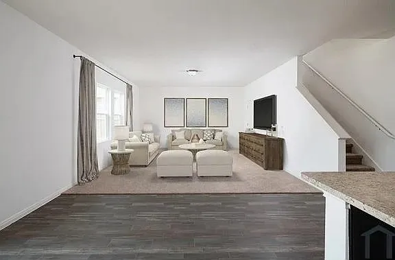 Wide plank wood-finish flooring extending into a carpeted living area