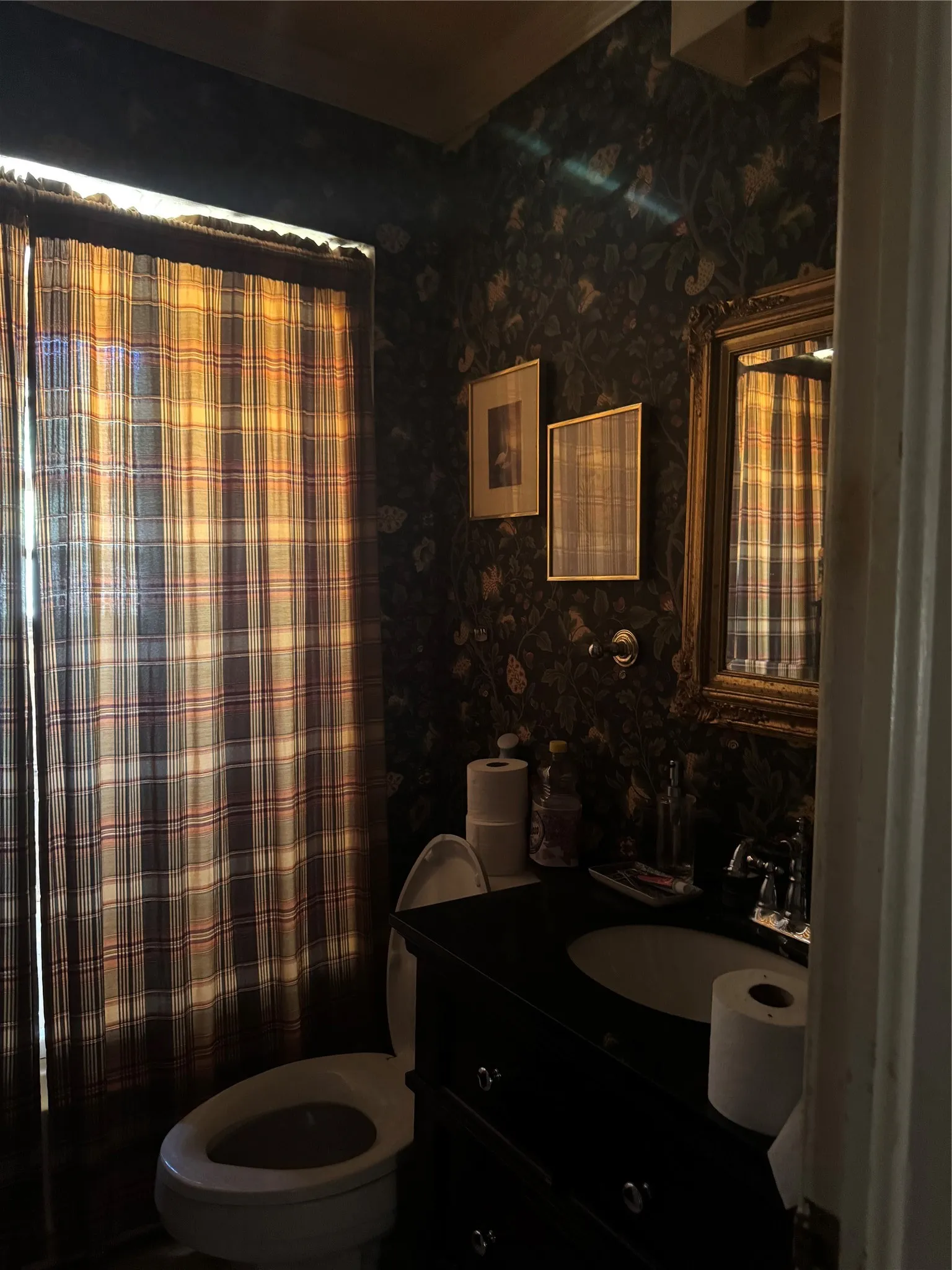 Vanity with integrated basin, ornate framed mirror, and decorative wall covering