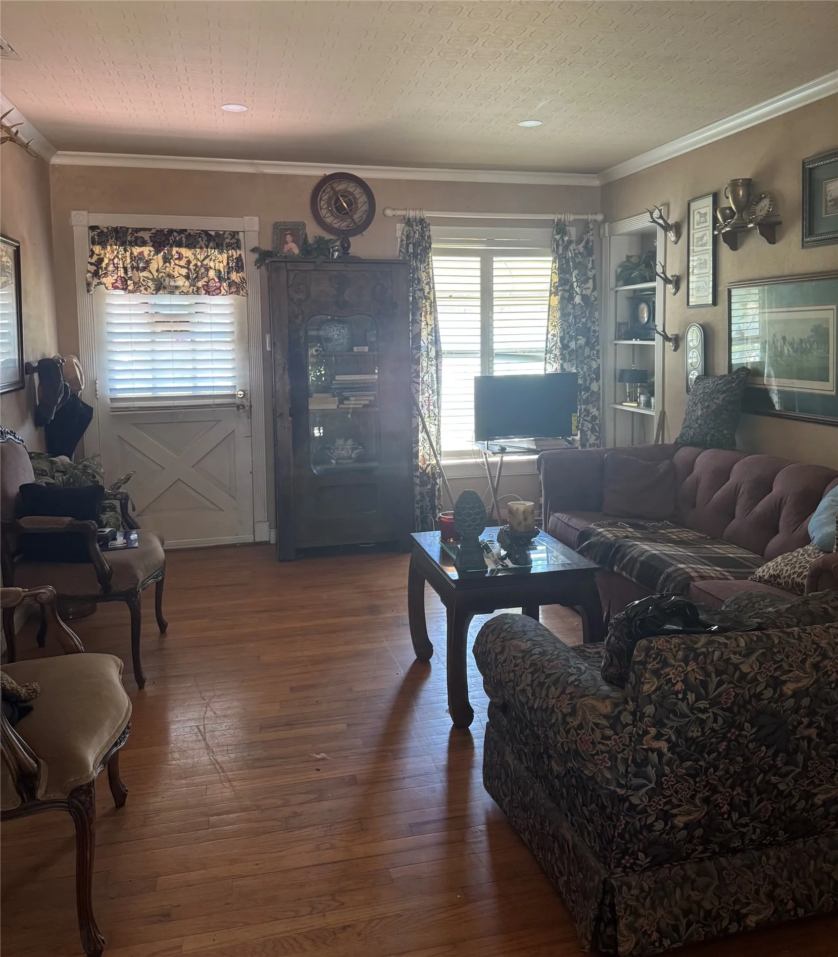 Hardwood flooring, crown molding, built-in shelving, two windows, and a Dutch door