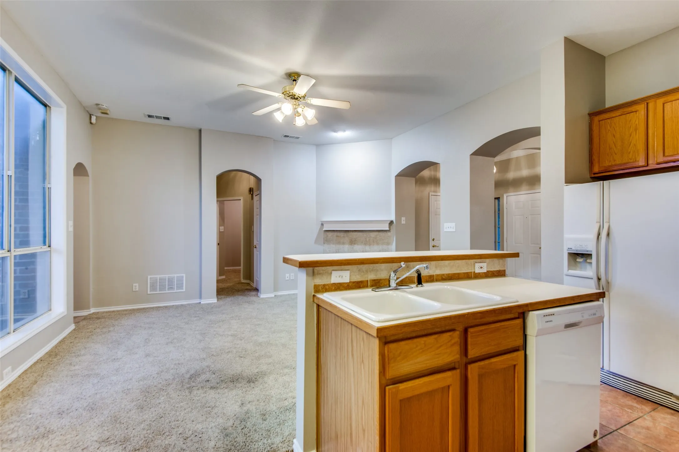 Kitchen featuring a dual basin sink, light wood-finish cabinetry, and a dishwasher
