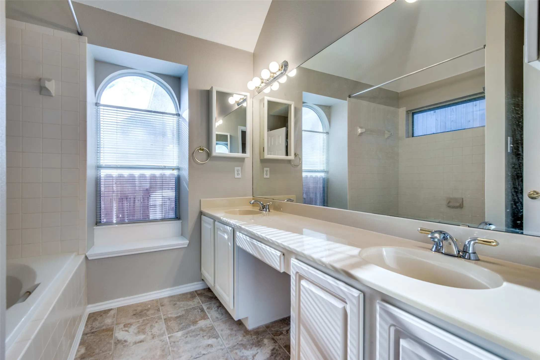 Double vanity with integrated sinks, ample countertop space, full-width mirror, and dedicated vanity lighting