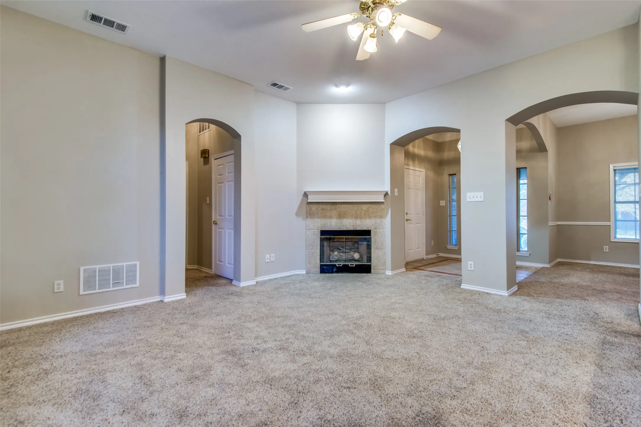 Carpeted living area with a built-in fireplace, tile surround, and mantel