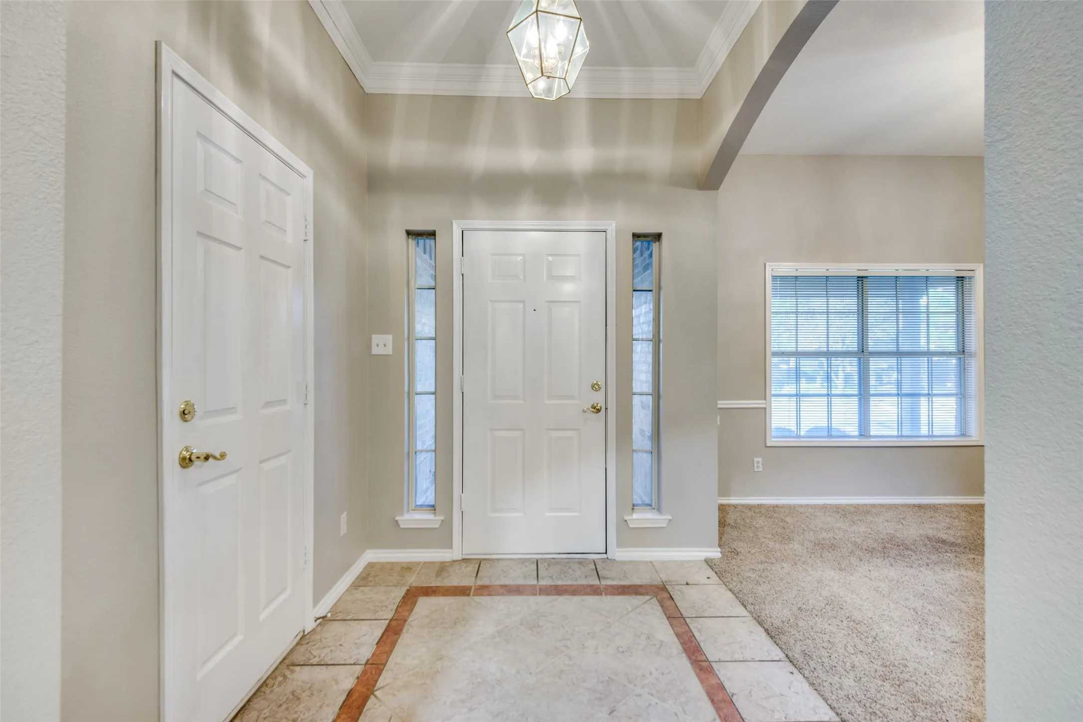 Entryway featuring a decorative ceiling light, tiled flooring with an accent border, and a transom window above the front door