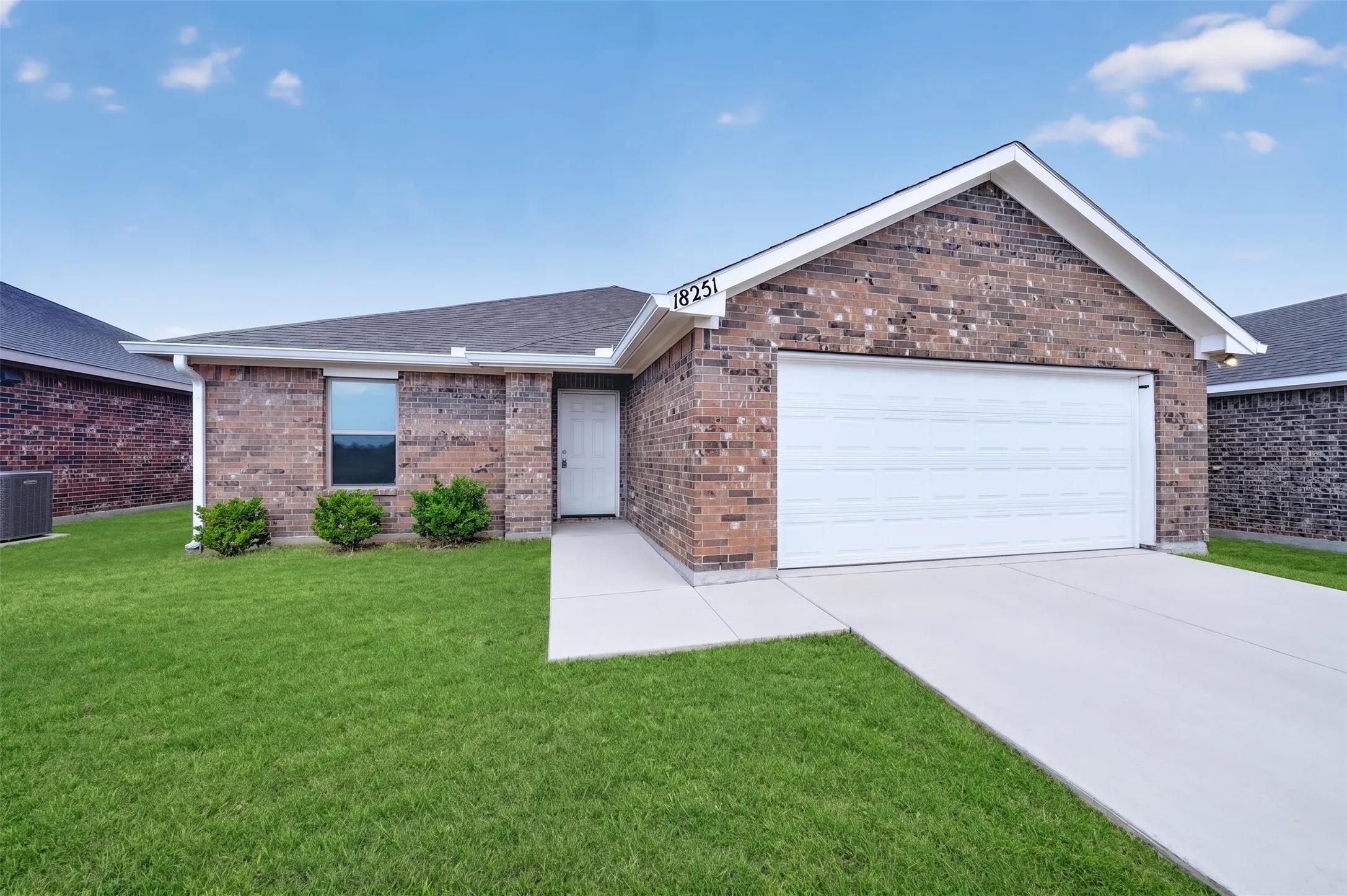 Brick exterior, attached garage, concrete driveway, and front walkway