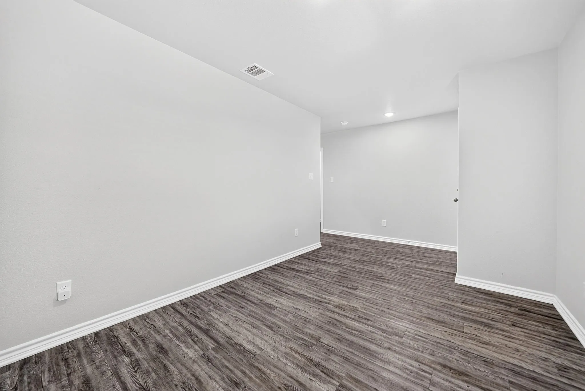 Wood-finish flooring with white baseboards and recessed ceiling lighting