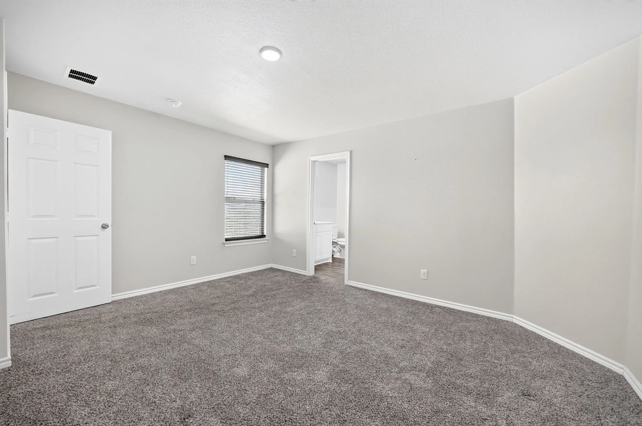Carpeted room with a single window featuring blinds, a white paneled door, and recessed ceiling lighting