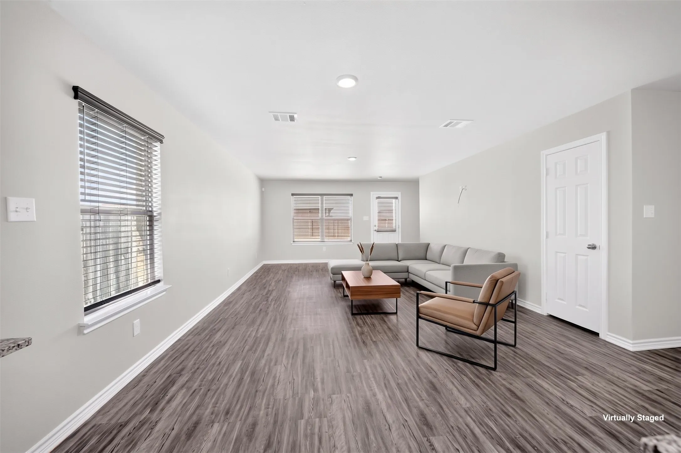 Wood-finish flooring throughout, multiple windows with blinds, recessed lighting, and a white paneled door