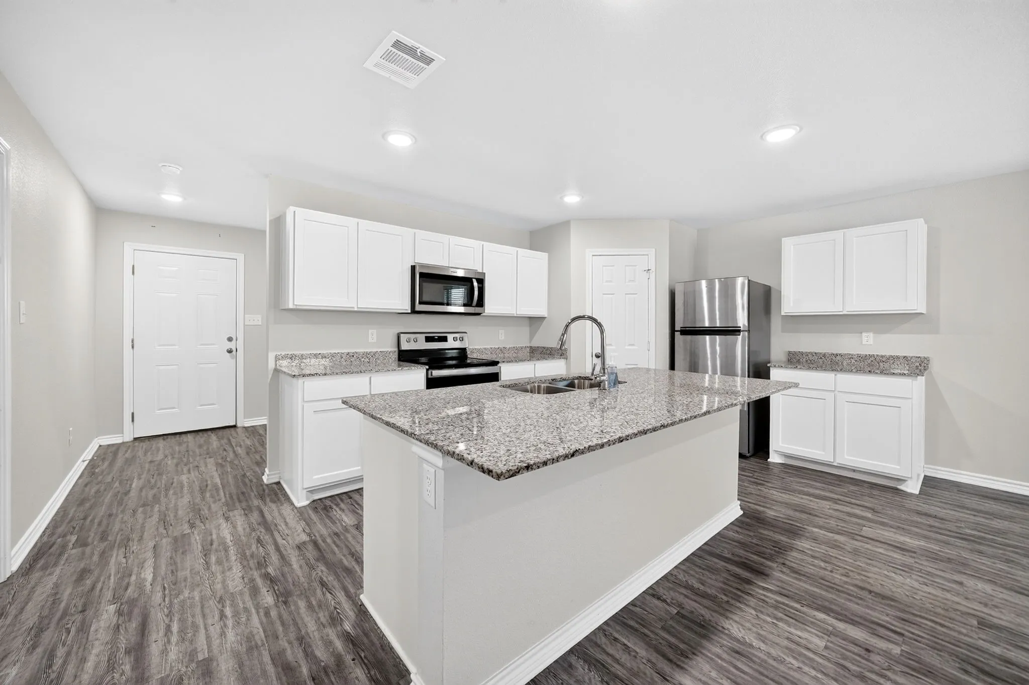 Kitchen featuring a central island, recessed lighting, white cabinetry, integrated stainless steel appliances, and wood-finish flooring