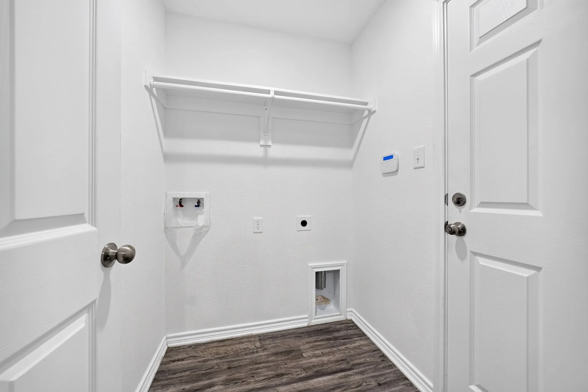 Laundry area featuring wood-finish flooring and built-in shelving