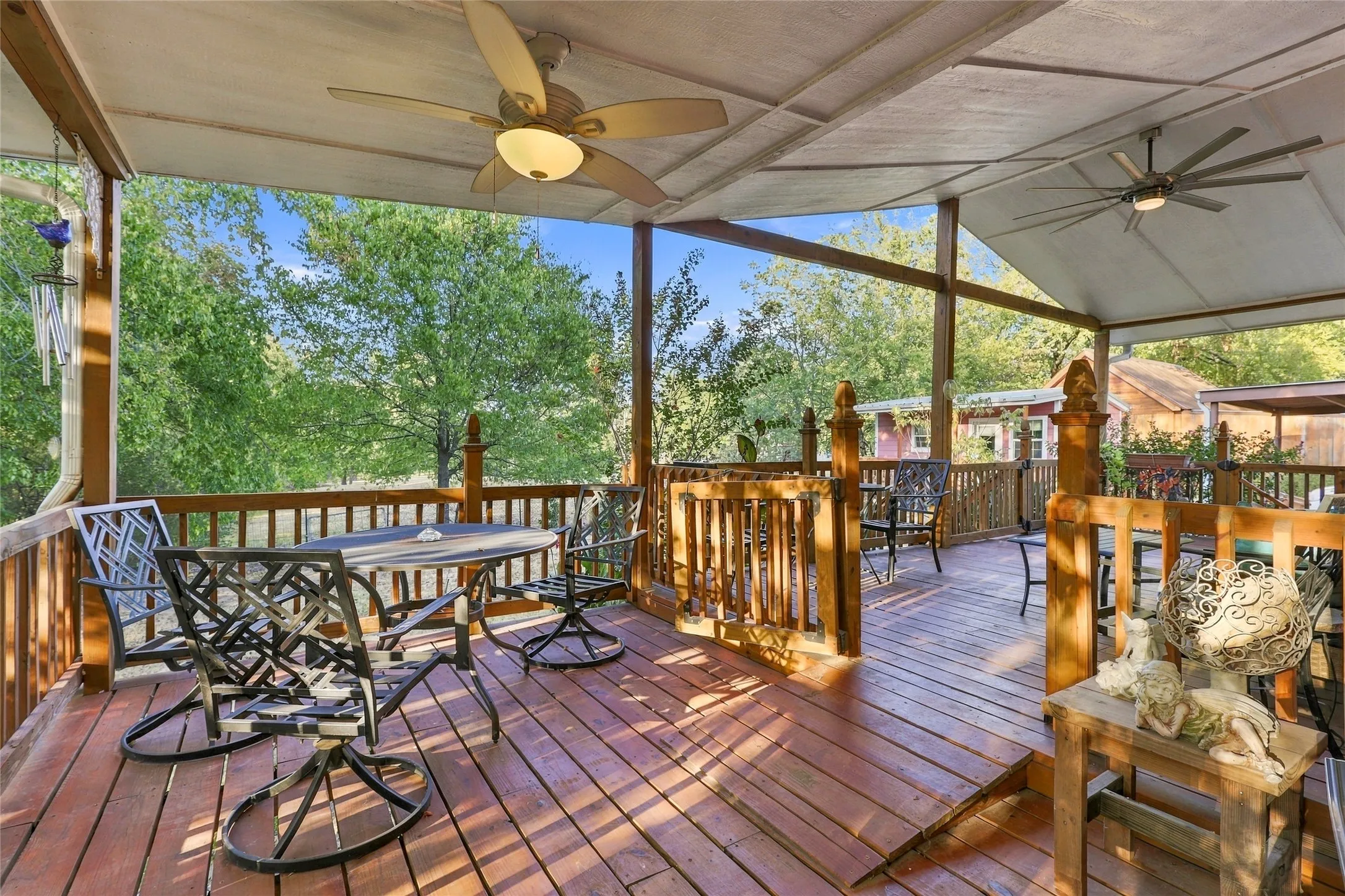 Expansive covered deck featuring wood-finish flooring, two ceiling fans, and wood railings