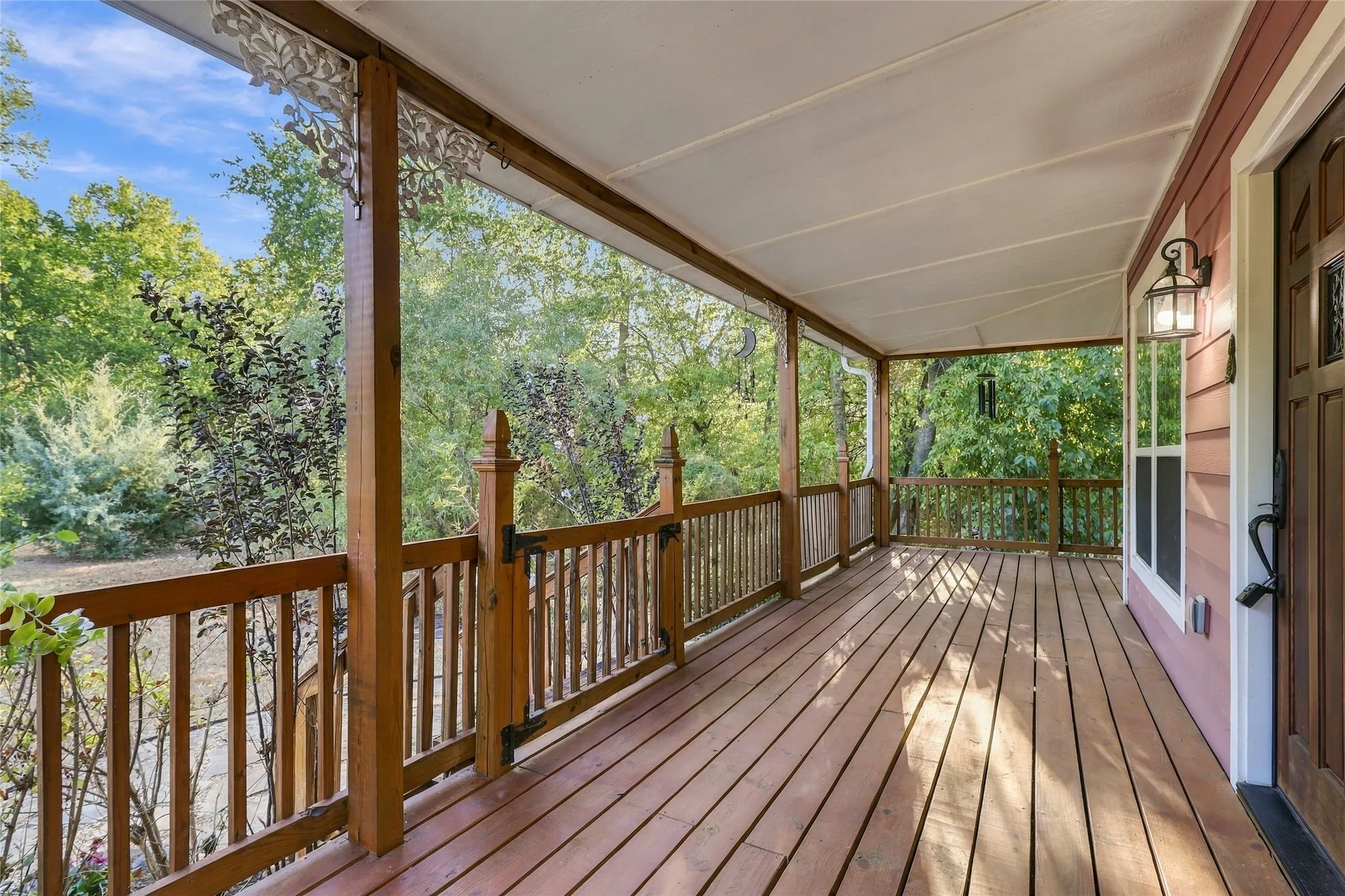 Expansive covered porch featuring wood flooring, wood railing, and decorative corbels
