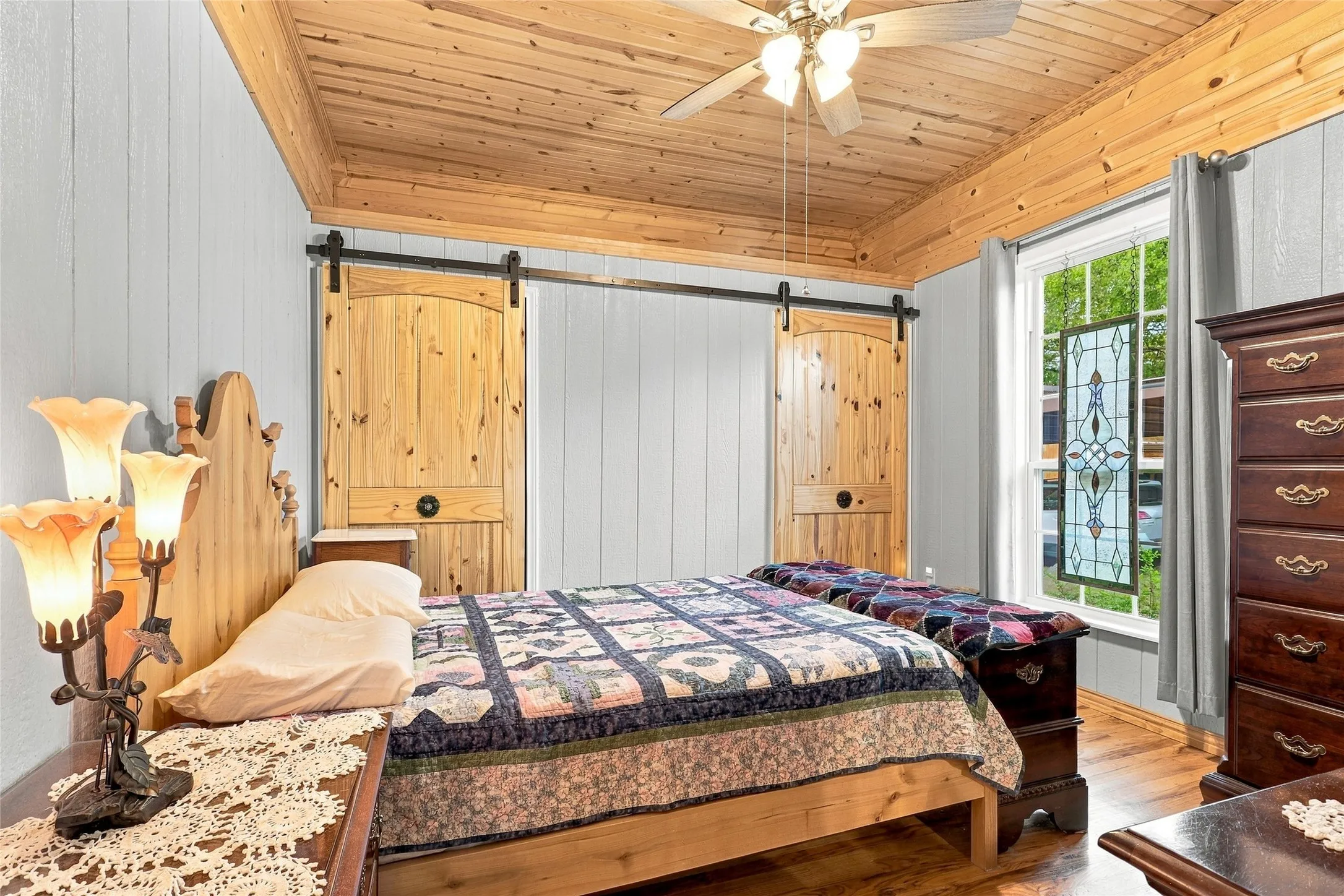 Wood-plank ceiling with a ceiling fan, light-toned wood-finish flooring, and white vertical paneled walls