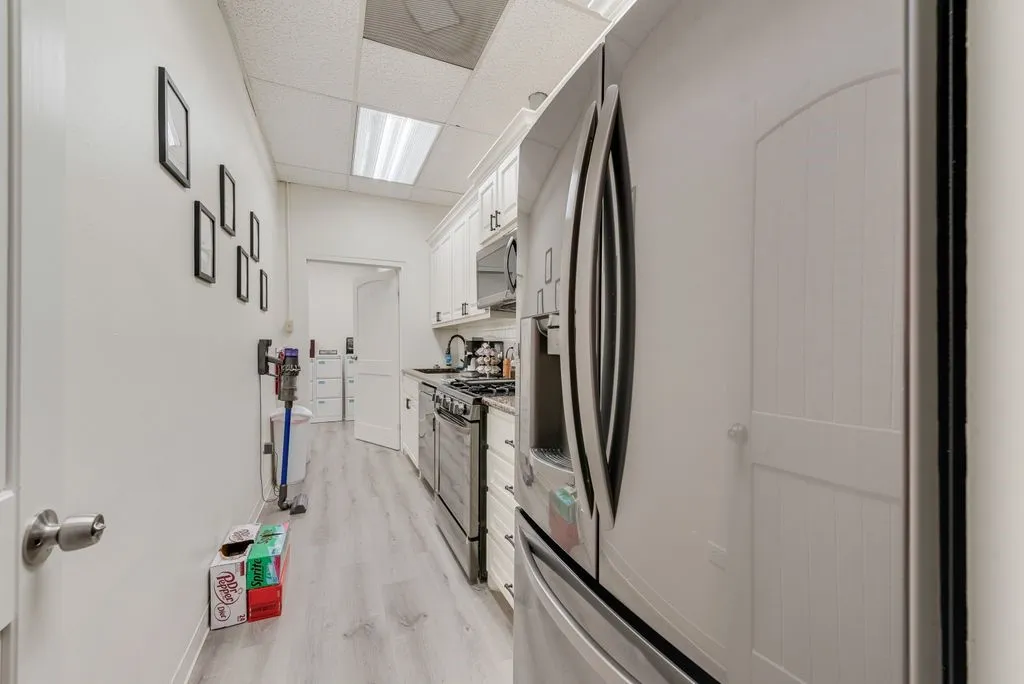 Galley kitchen featuring wood-finish flooring, white cabinetry, and stainless-steel appliances