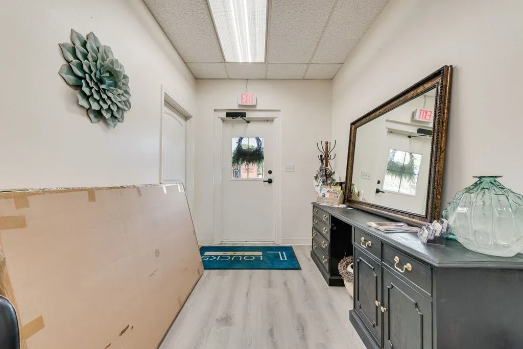 Wood-finish flooring with white walls and a white door with a window