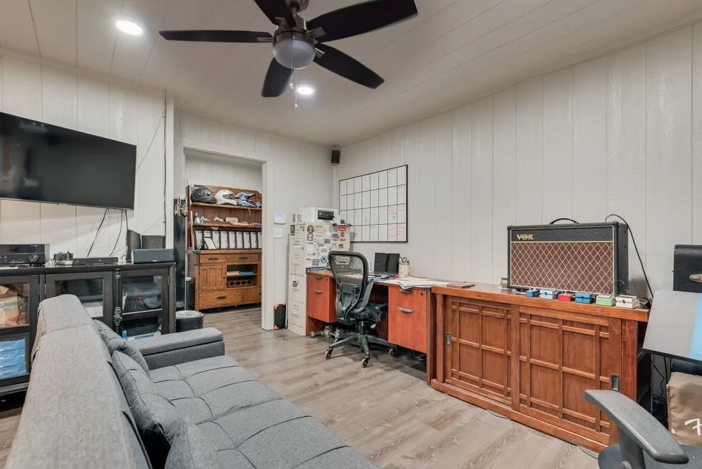 Wood-finish flooring, white paneled walls, and a ceiling fan with integrated lighting