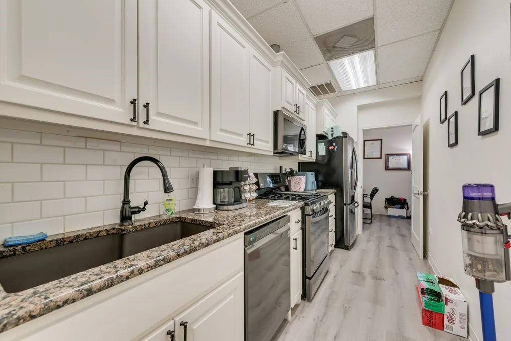 Kitchen featuring white cabinetry, granite-style countertops, subway tile backsplash, and stainless steel appliances