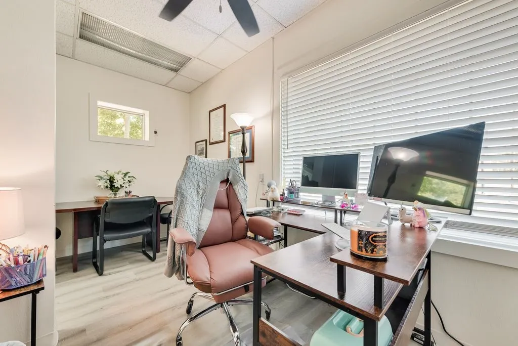 Light-colored wood-finish flooring, white walls, and a drop ceiling with integrated lighting