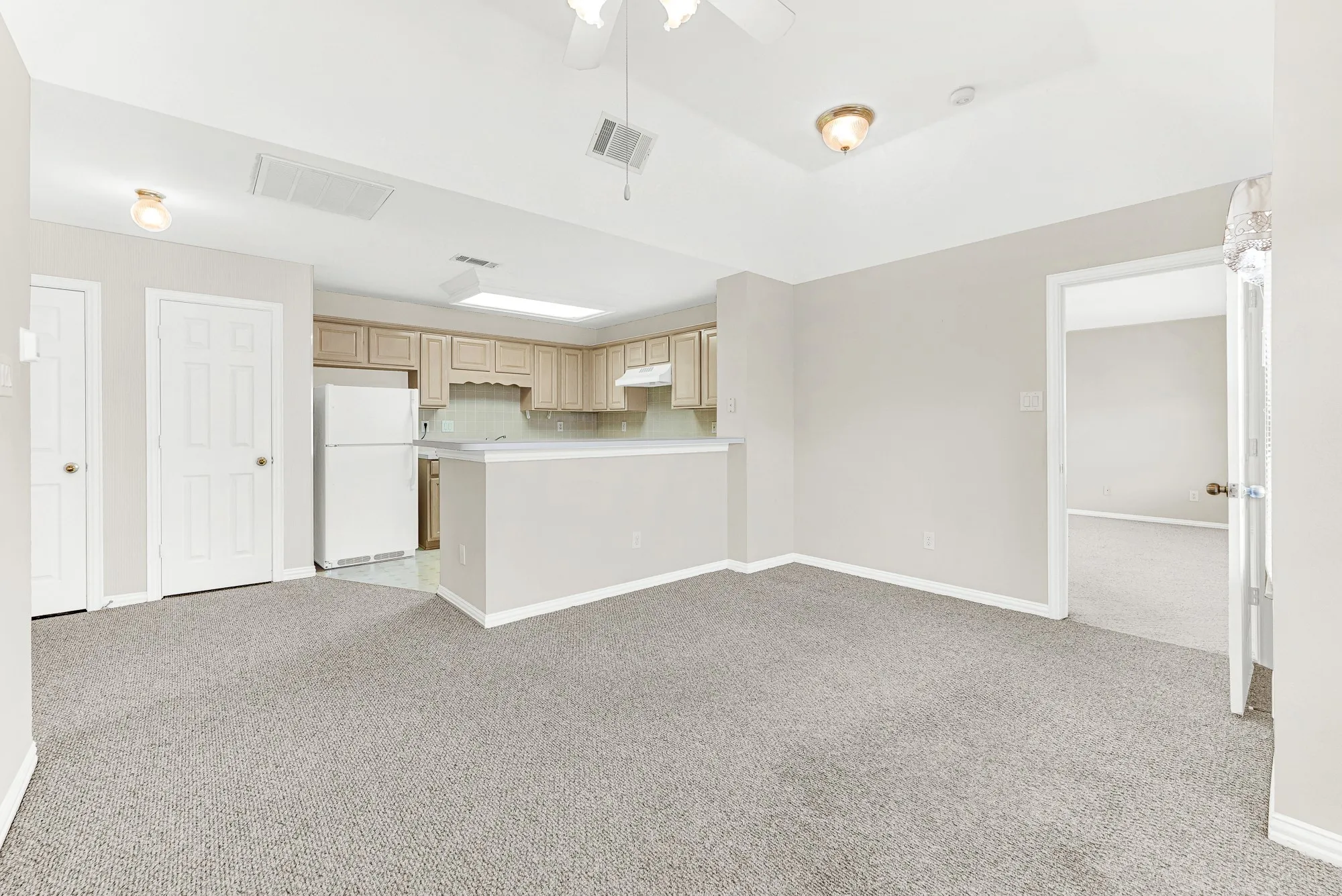 The open living zone flows effortlessly toward both the private bedroom suite entrance and the dedicated kitchen area. Enjoy quiet independence while staying connected under the same roof