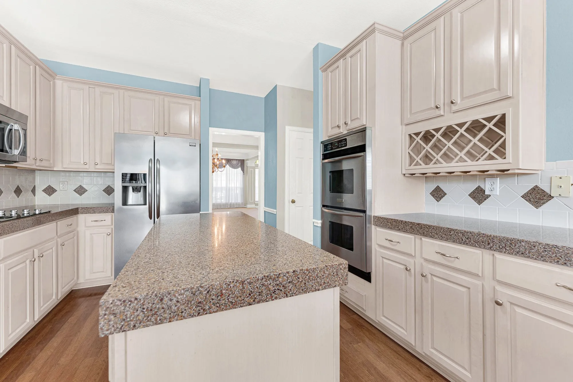A built-in double oven and lattice wine rack seamlessly anchor the functional prep perimeter. Imagine uncorking a favorite vintage while simmering sauce on a relaxing evening.