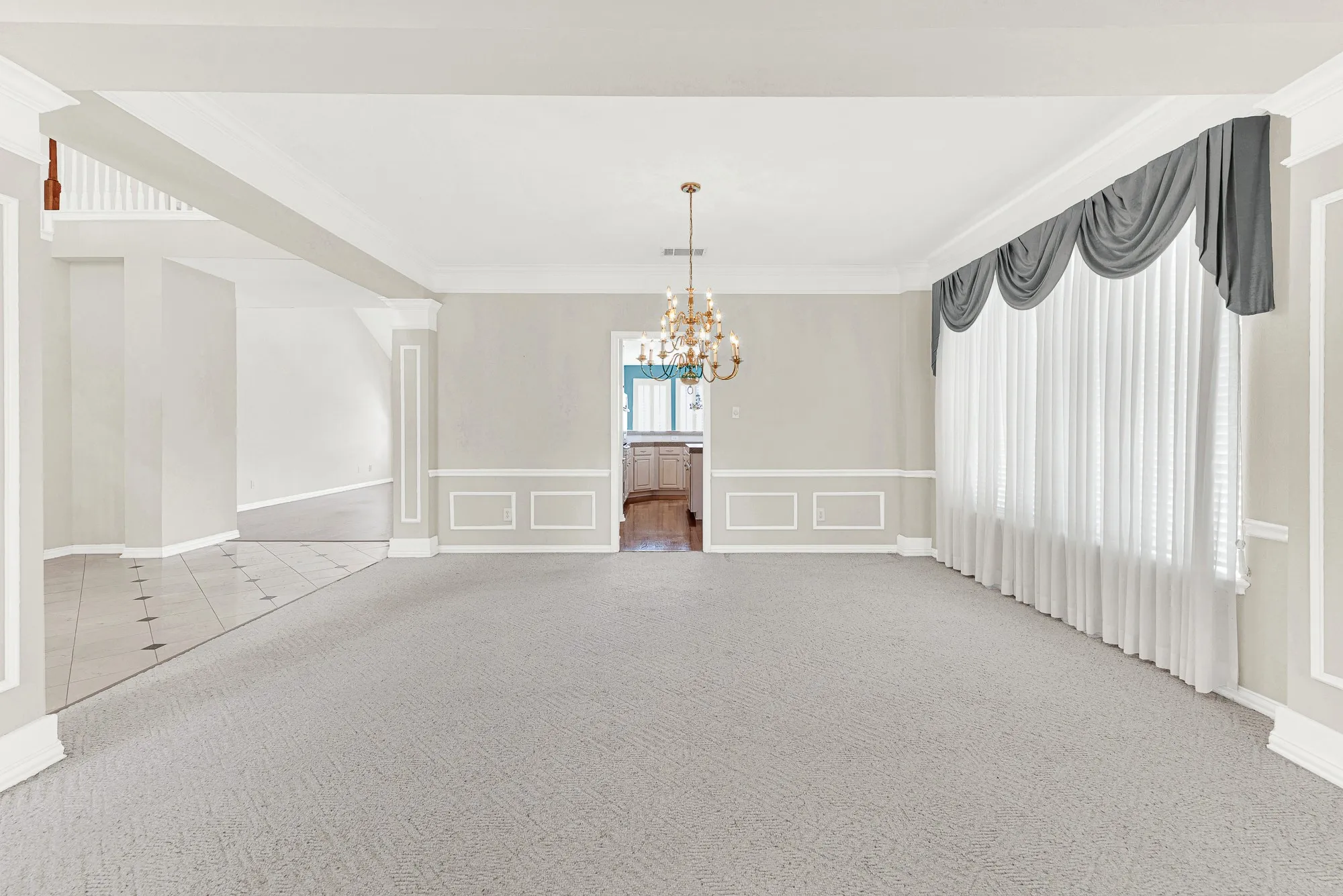 Generous picture windows draped in soft shear curtains filter gentle, ambient light across the refined wall molding. You can easily picture setting a large table under the chandelier for memorable holiday feasts.