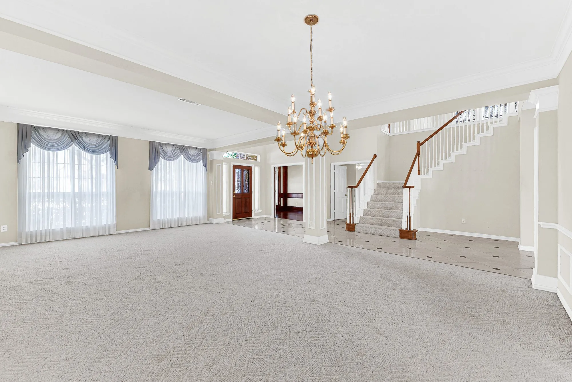 An ornate brass chandelier serves as a graceful central anchor above the vast expanse of soft carpet. It offers a warm setting to unwind with a good book on a quiet weekend afternoon.