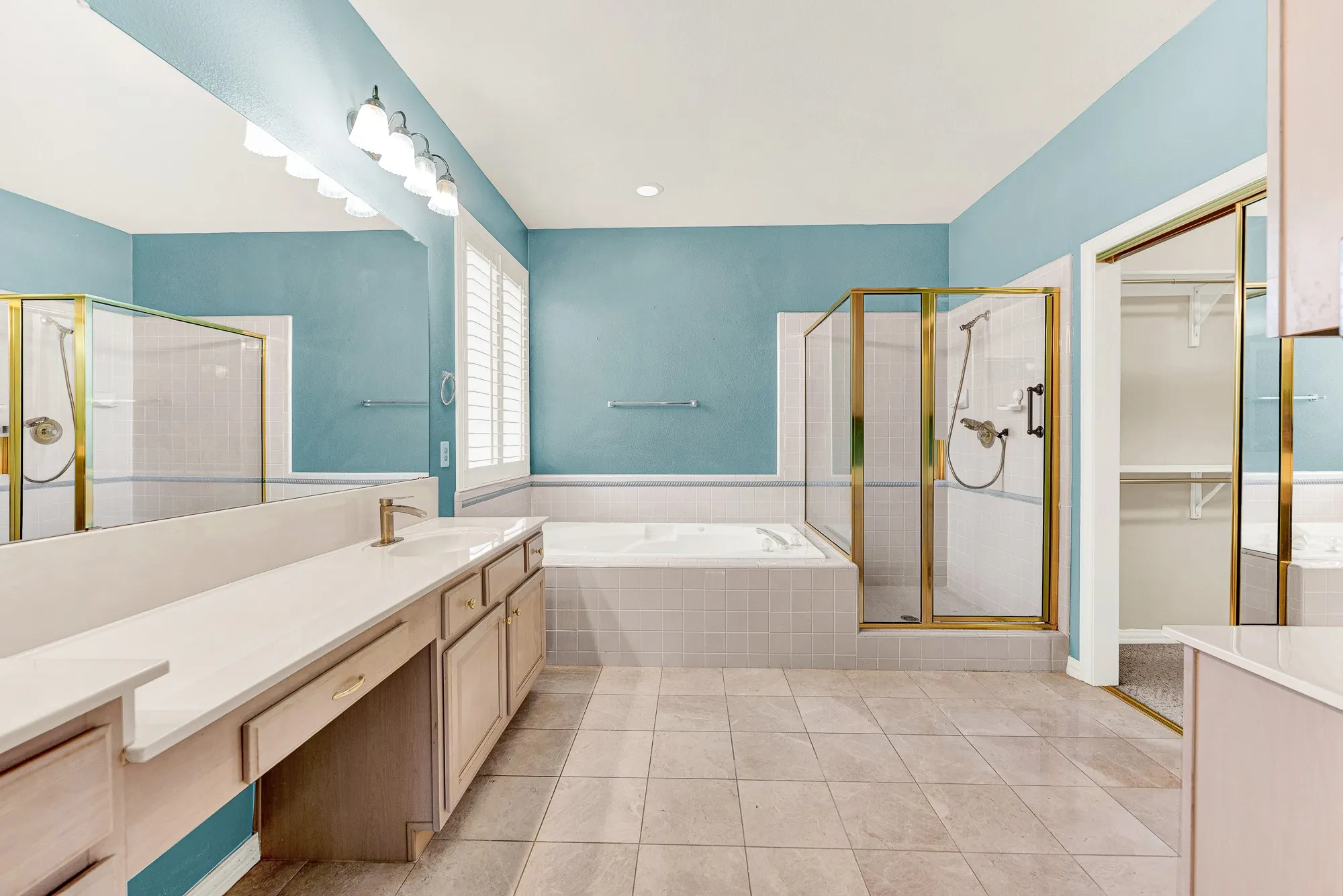A deep soaking tub and glass shower stall are nestled against tranquil sky-blue walls. Treat yourself to a relaxing spa-like bath at the end of the wee