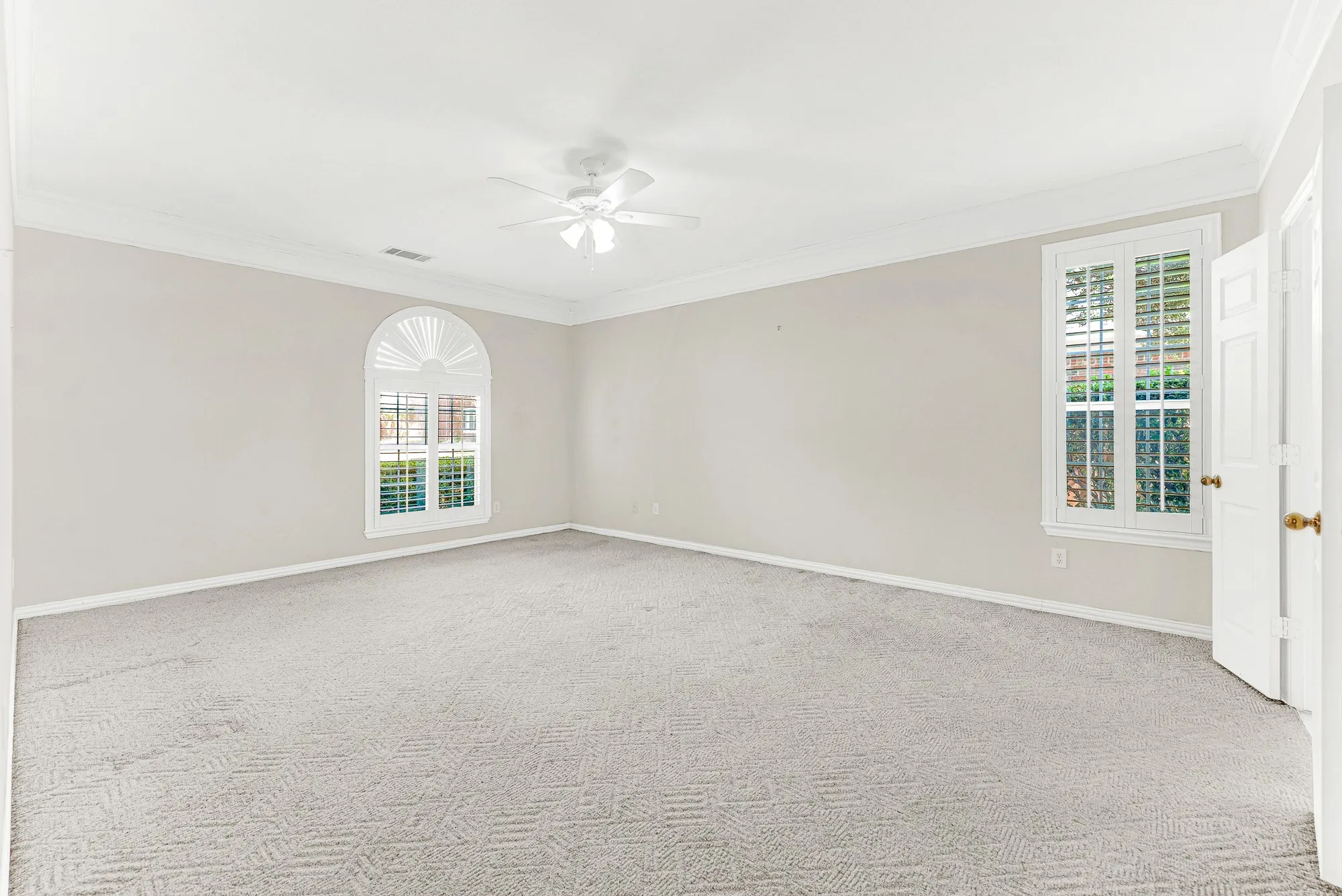 A classic arched window with custom shutters provides a focal point against muted neutral walls in this ground-floor primary retreat. Wake up refreshed as soft daylight gently fills the room each morning