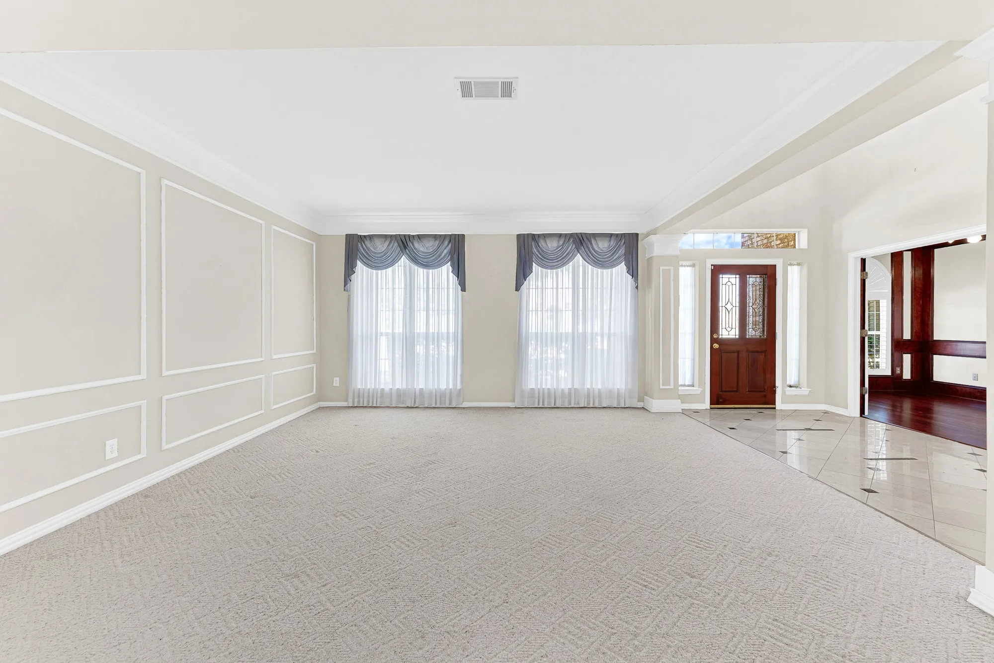 Clean wall paneling and dual framed windows establish a balanced, symmetrical backdrop bathed in natural daylight. This versatile layout invites you to kick off your shoes and enjoy casual family game nights.