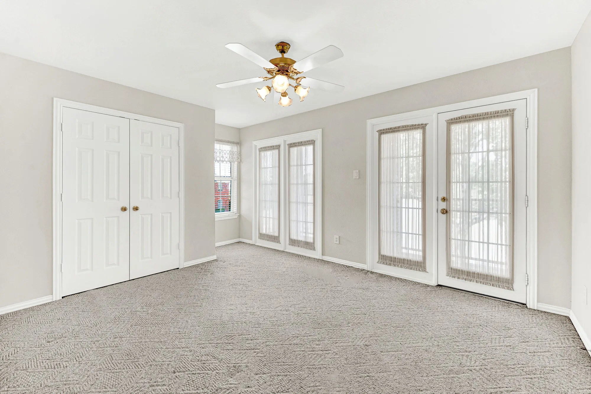 This spacious second-floor bedroom features plush neutral carpeting, a double-door closet, and two sets of French doors opening directly out to the upper balcony. Wake up to soft natural light and enjoy effortless indoor-outdoor flow right from your bedroom.