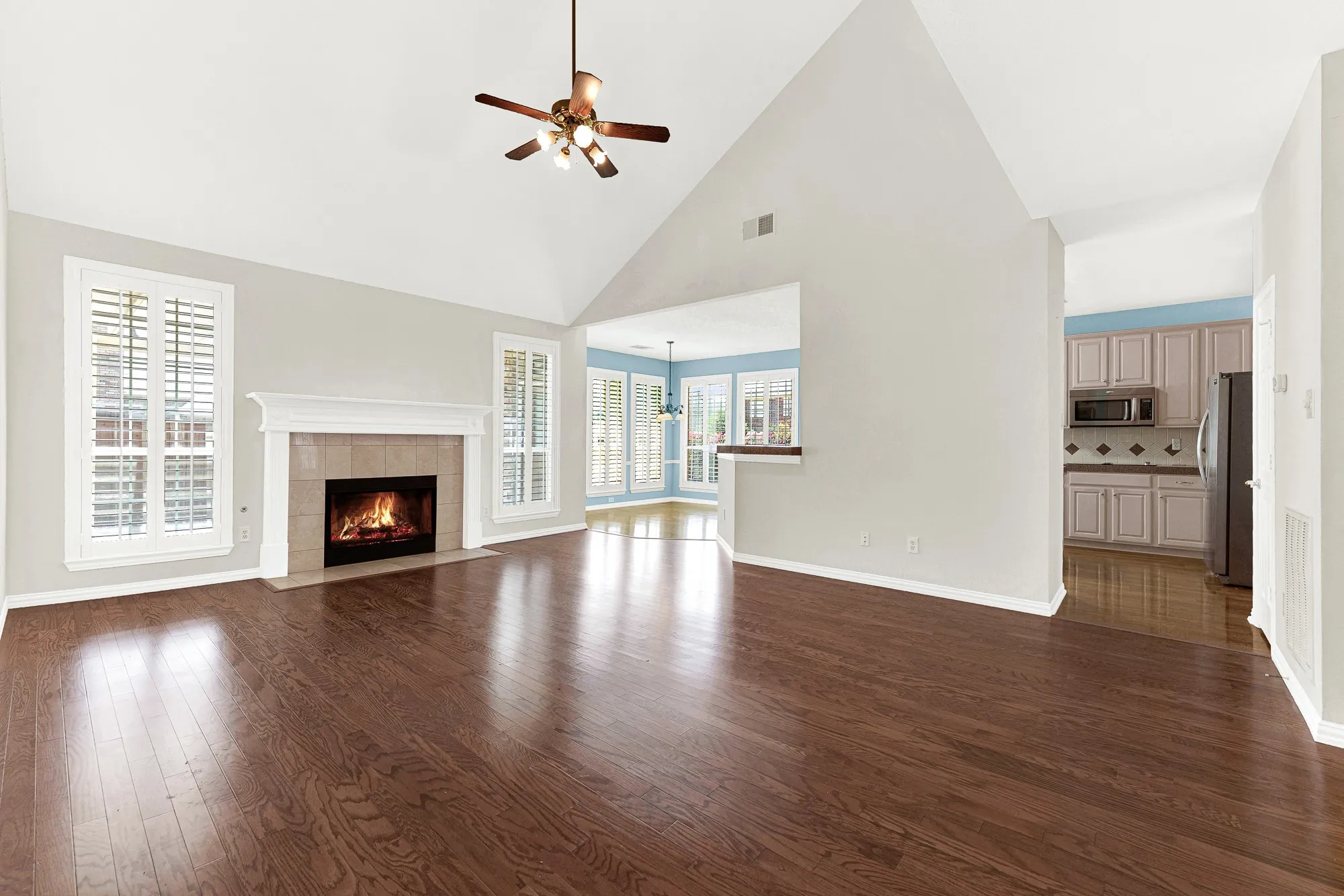 A dramatic vaulted ceiling draws the eye upward while a central tile hearth casts a warm glow across glowing wood floors. Picture curling up here with a mug of hot cocoa on a crisp autumn evening.