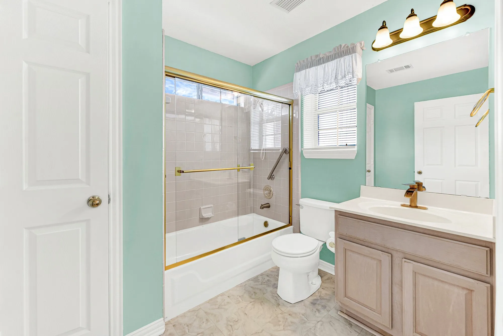 Refreshing seafoam green walls frame a full tub-and-shower combination and single vanity. Pamper yourself in complete comfort within your own private bath