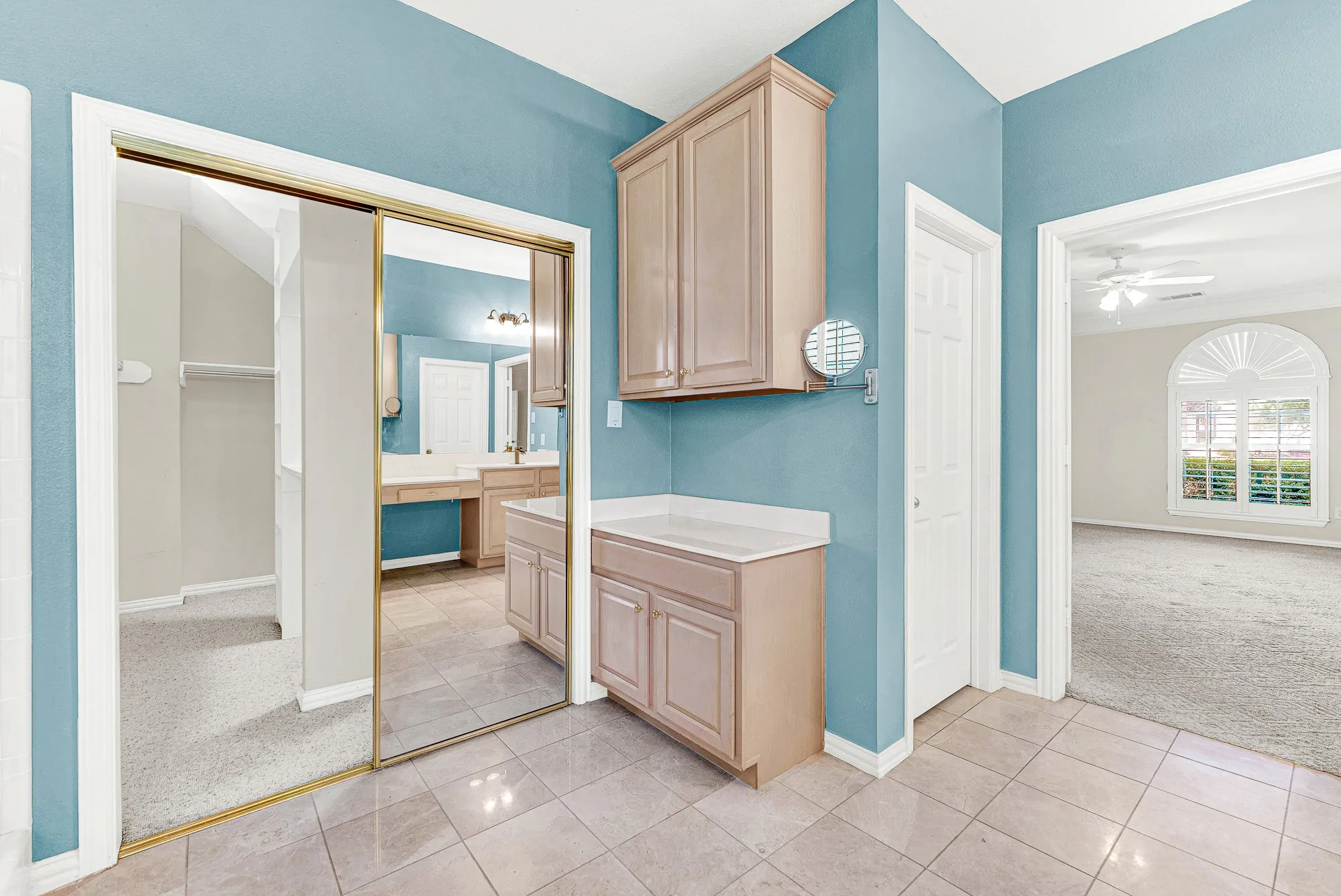 Mirrored closet doors expand the tiled dressing area near the primary bedroom entrance. Get ready effortlessly with extra storage right at your fingertips.