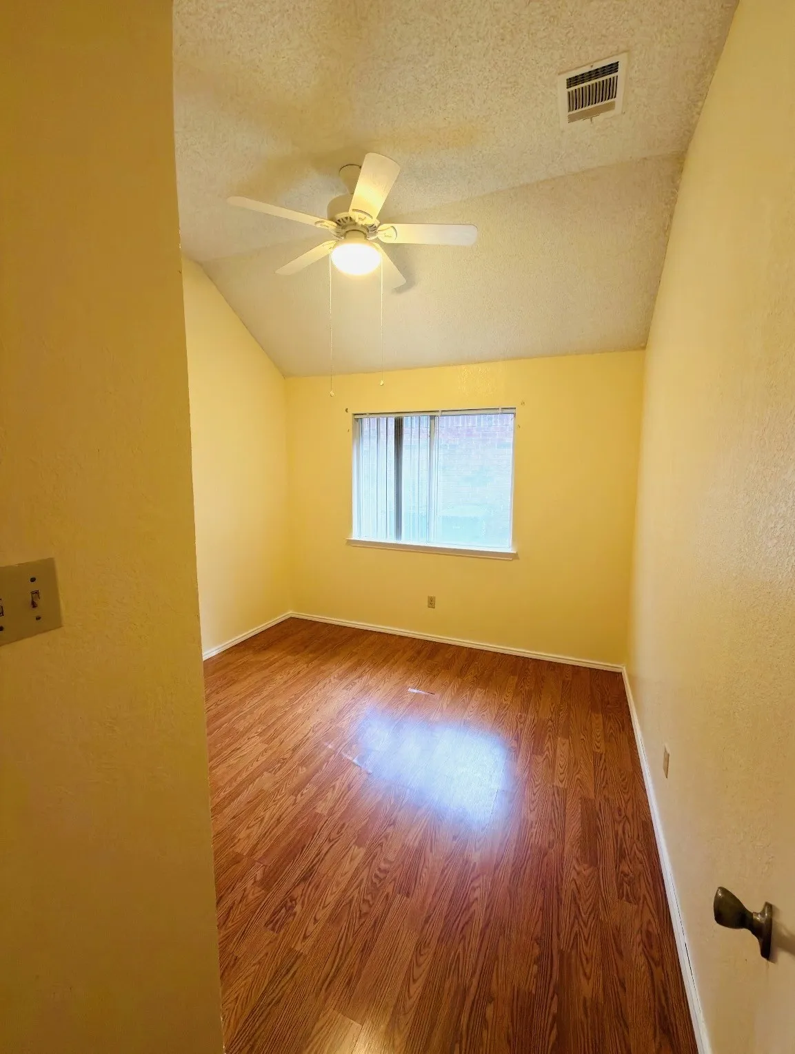 Vaulted ceiling with a ceiling fan, wood-finish flooring, and a window with blinds
