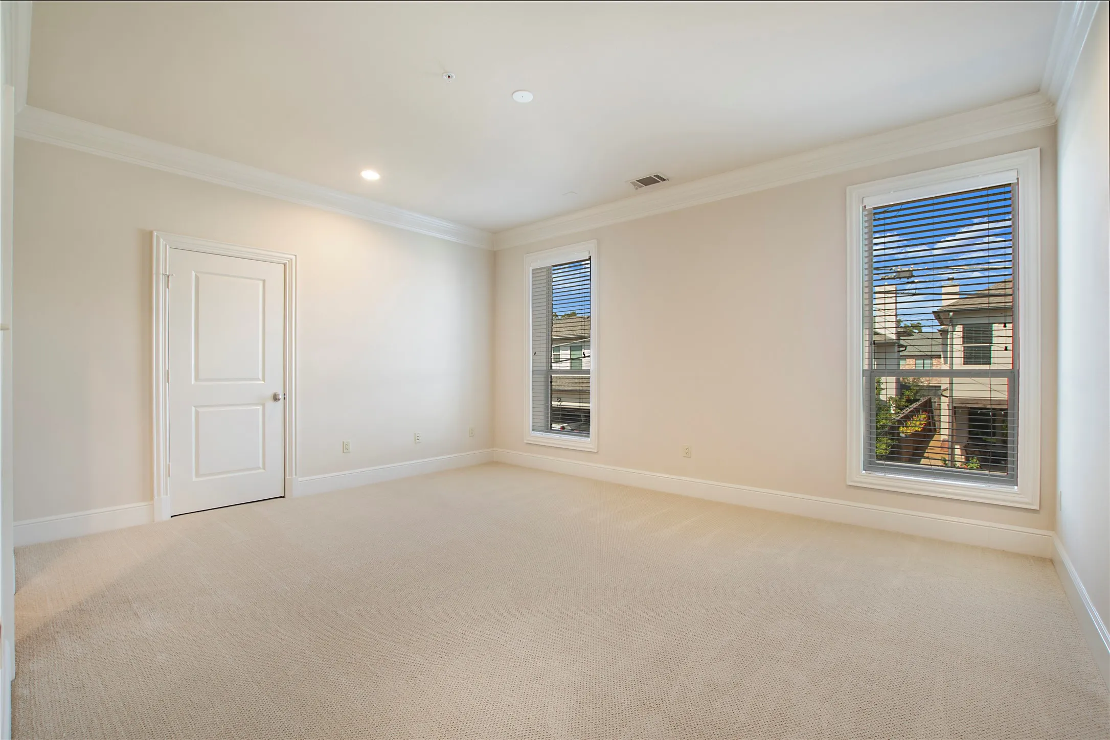 Empty room with light colored carpet and a healthy amount of sunlight