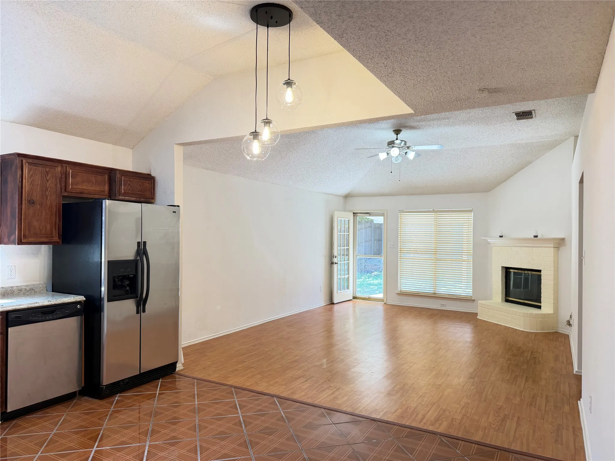 Vaulted ceilings, wood-finish flooring, and a corner fireplace with a mantel
