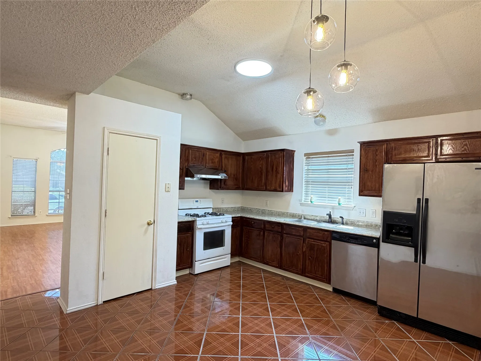 Kitchen featuring wood cabinetry, stainless steel appliances, a white gas range, and patterned tile flooring