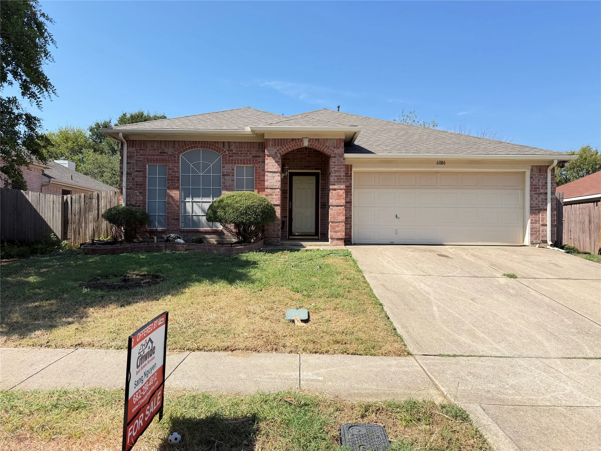 Brick facade, arched entry, arched window, two-car garage, concrete driveway