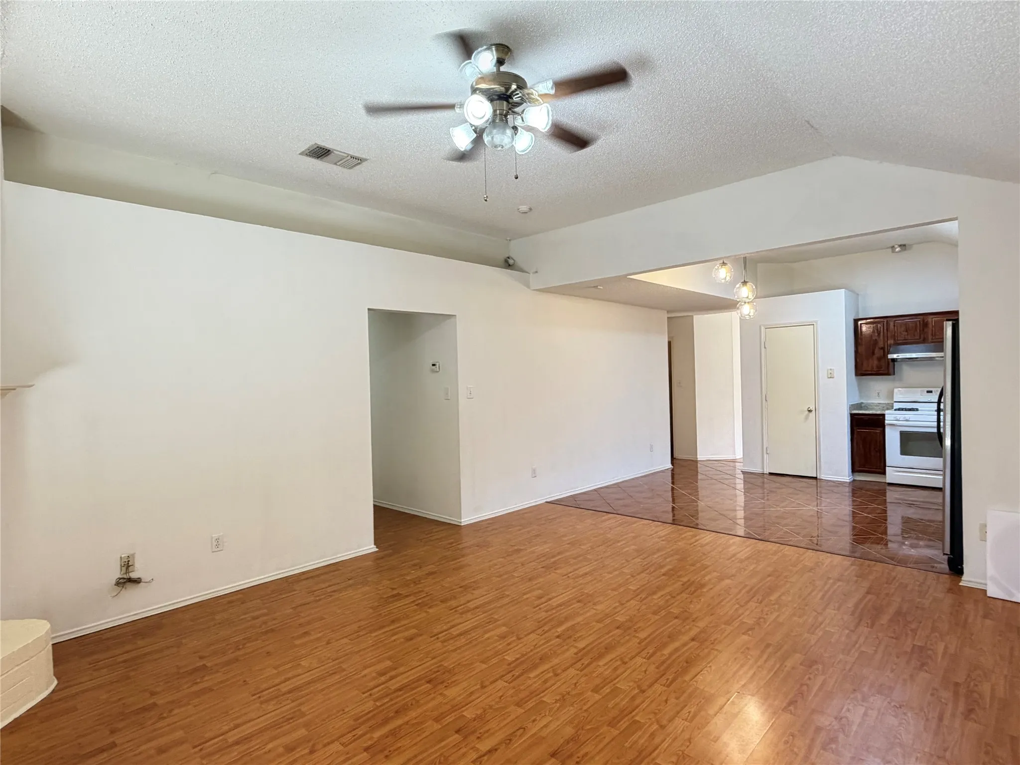 Recessed lighting, wood-finish flooring, ceiling fan, dark wood-finish cabinetry, and white appliances