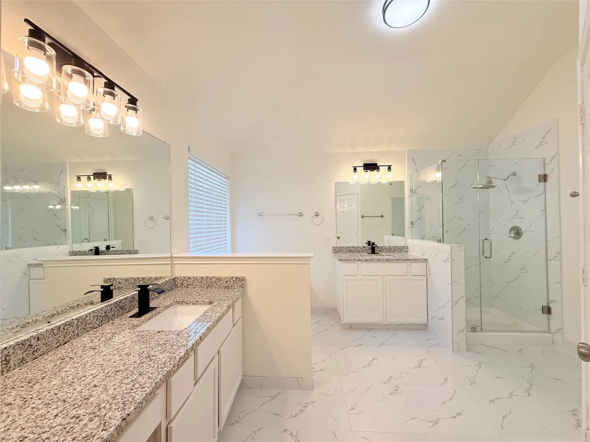 Dual vanities with granite countertops, white cabinetry, and matte black fixtures