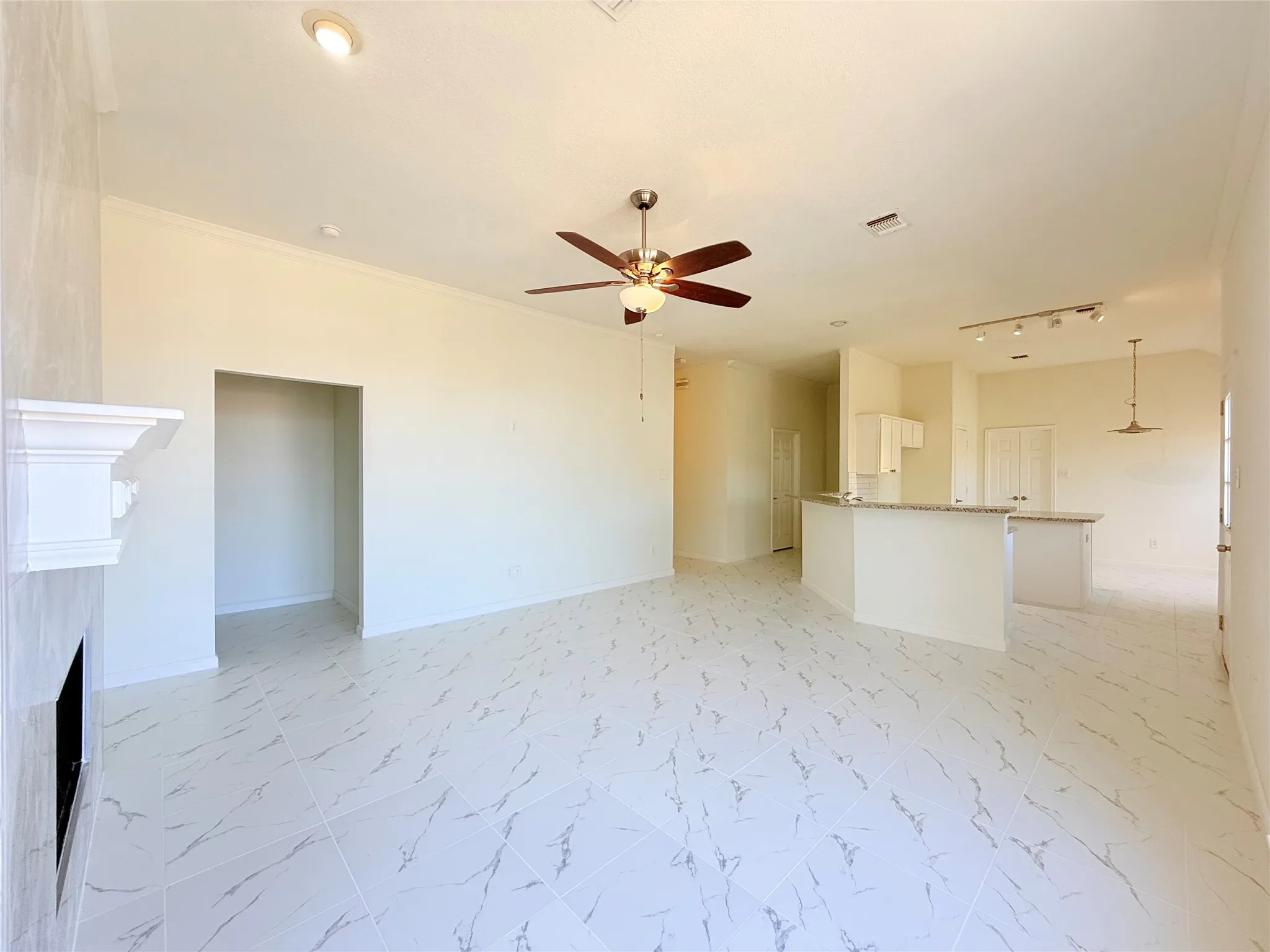 Open-concept living space featuring large format tile flooring, a built-in fireplace, a ceiling fan, and recessed lighting