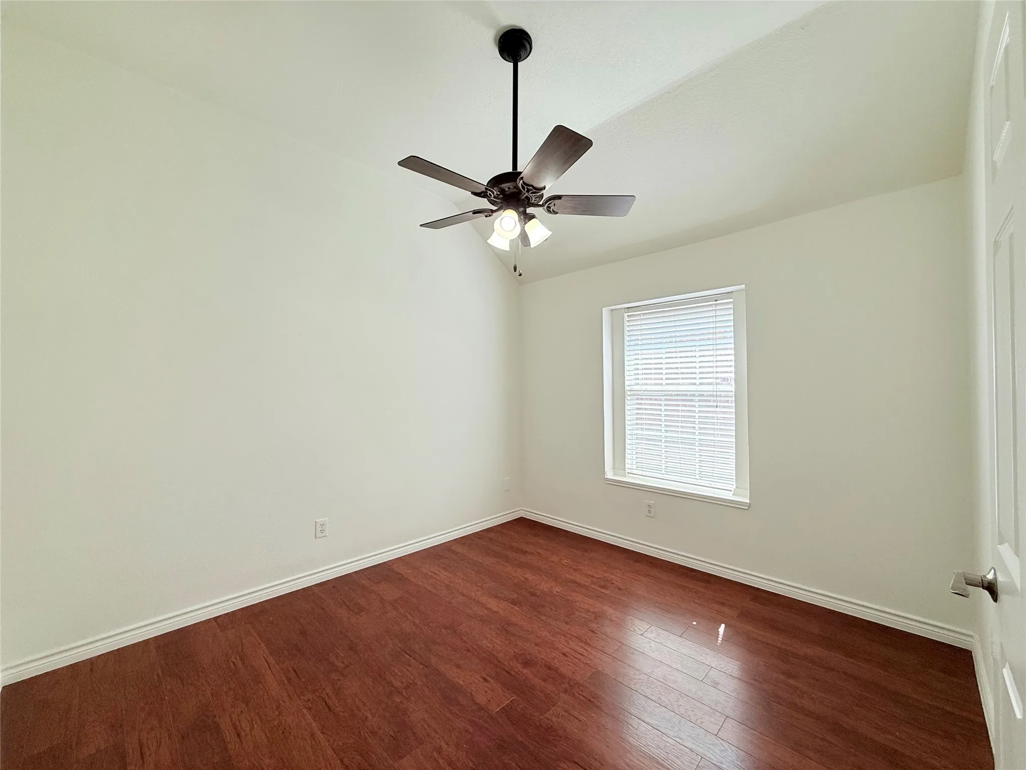 Wood-finish flooring, ceiling fan with integrated lighting, window with blinds, and a white interior door