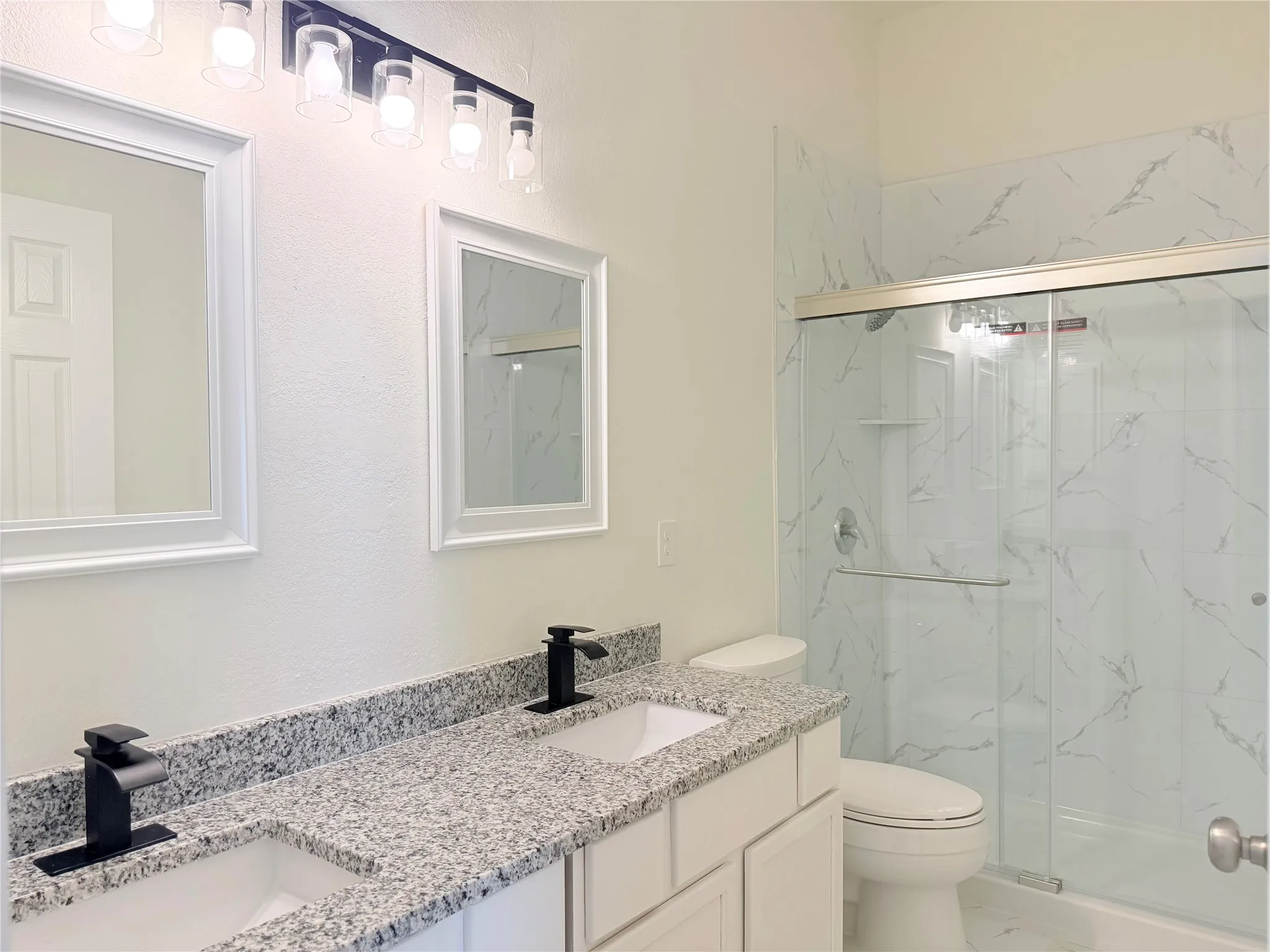 Double vanity with granite countertops, dual rectangular sinks, and matte black faucets