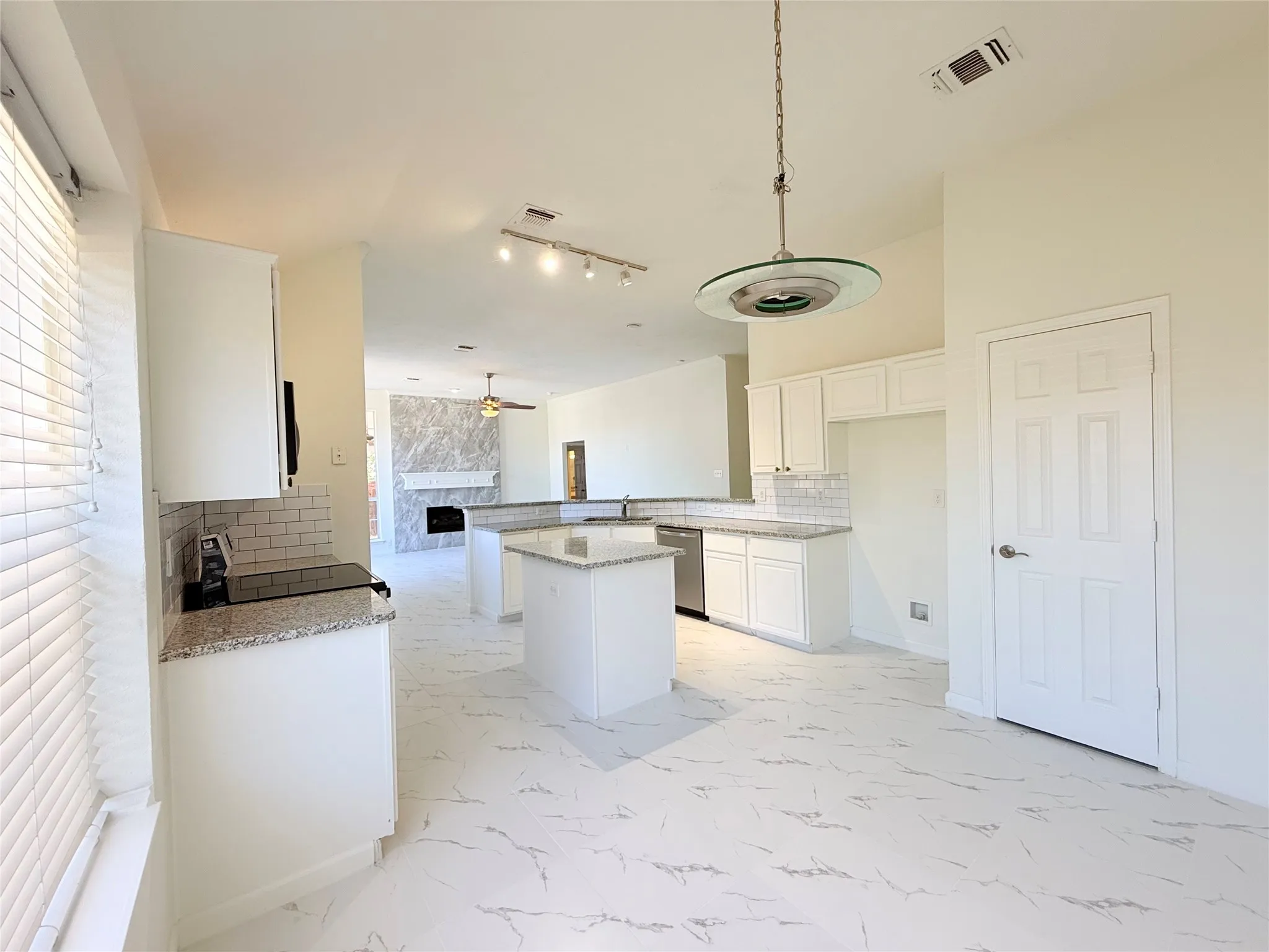 Open-concept kitchen featuring white cabinetry, light-toned countertops, and a central island