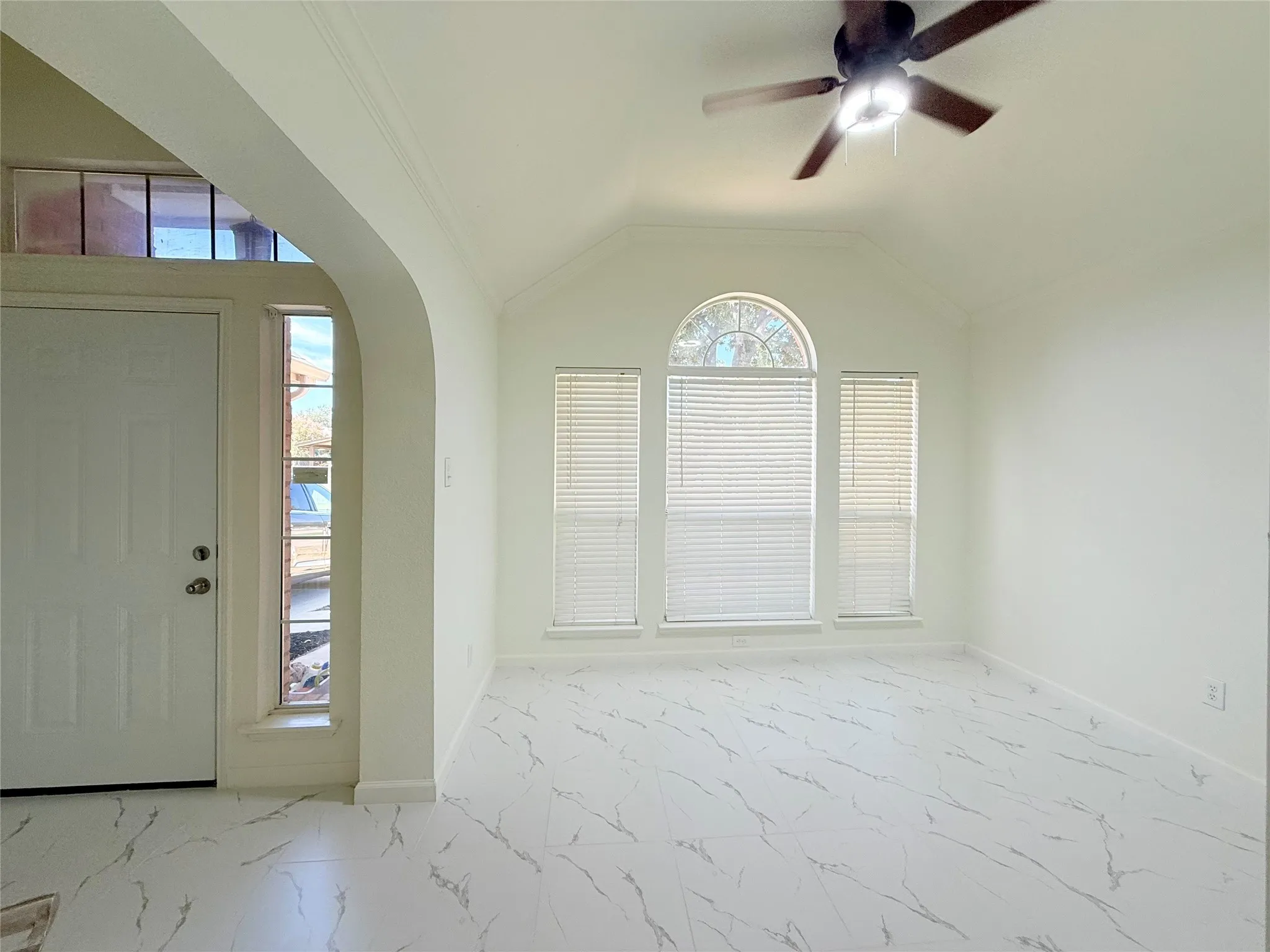 Vaulted ceiling with a ceiling fan, arched entryway, and white tile flooring