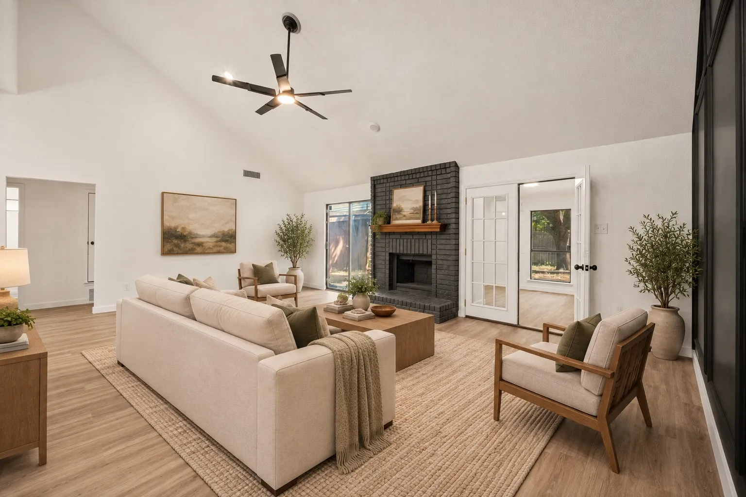 Vaulted ceiling, wood-finish flooring, brick fireplace with wood mantel, French doors, and black-framed windows