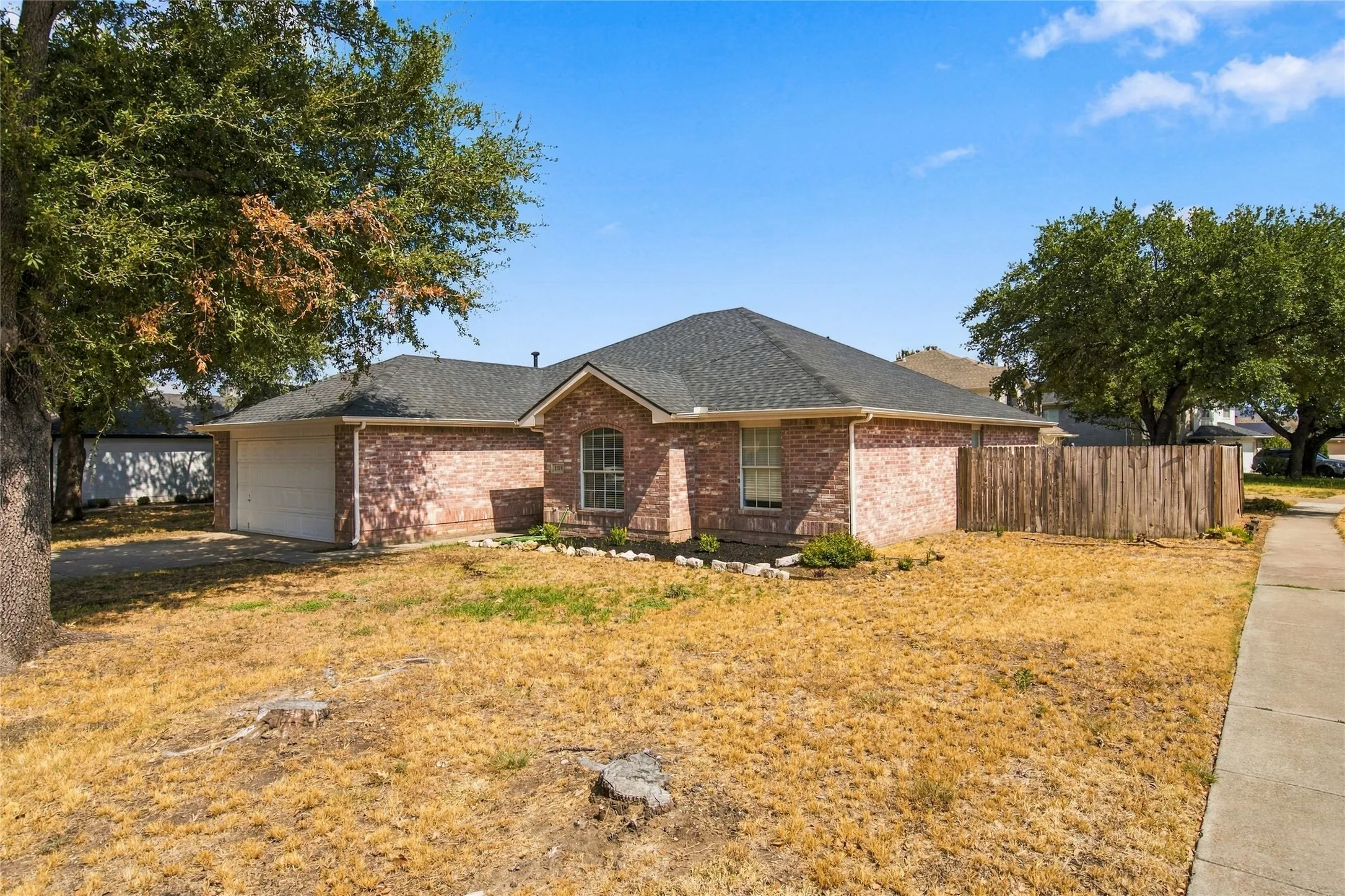 Brick exterior, attached two-car garage, fenced yard, and a shingle roof