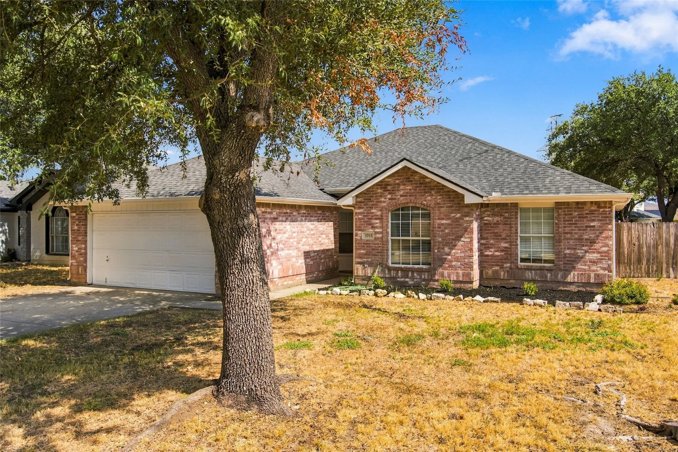 Brick exterior with an arched window, a two-car garage, and a gabled roofline