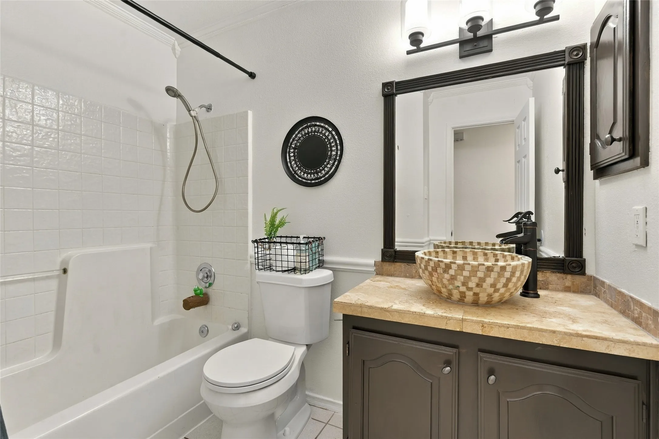 Bathroom featuring a shower-tub combination, a vanity with a vessel sink, a stone-finish countertop, and a dark wood-finish cabinet
