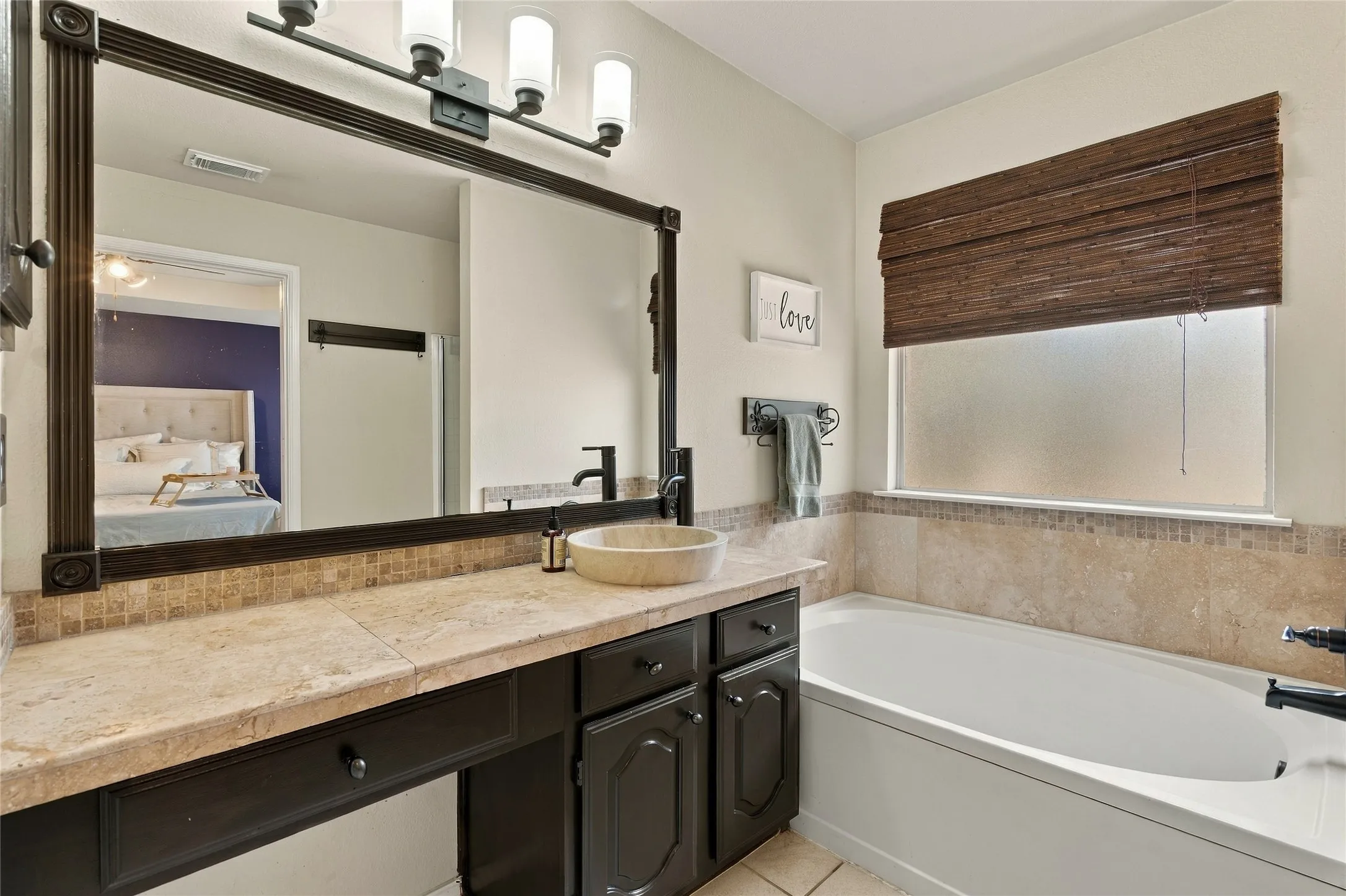 Built-in vanity with stone countertop, vessel sink, and full-width mirror with decorative lighting