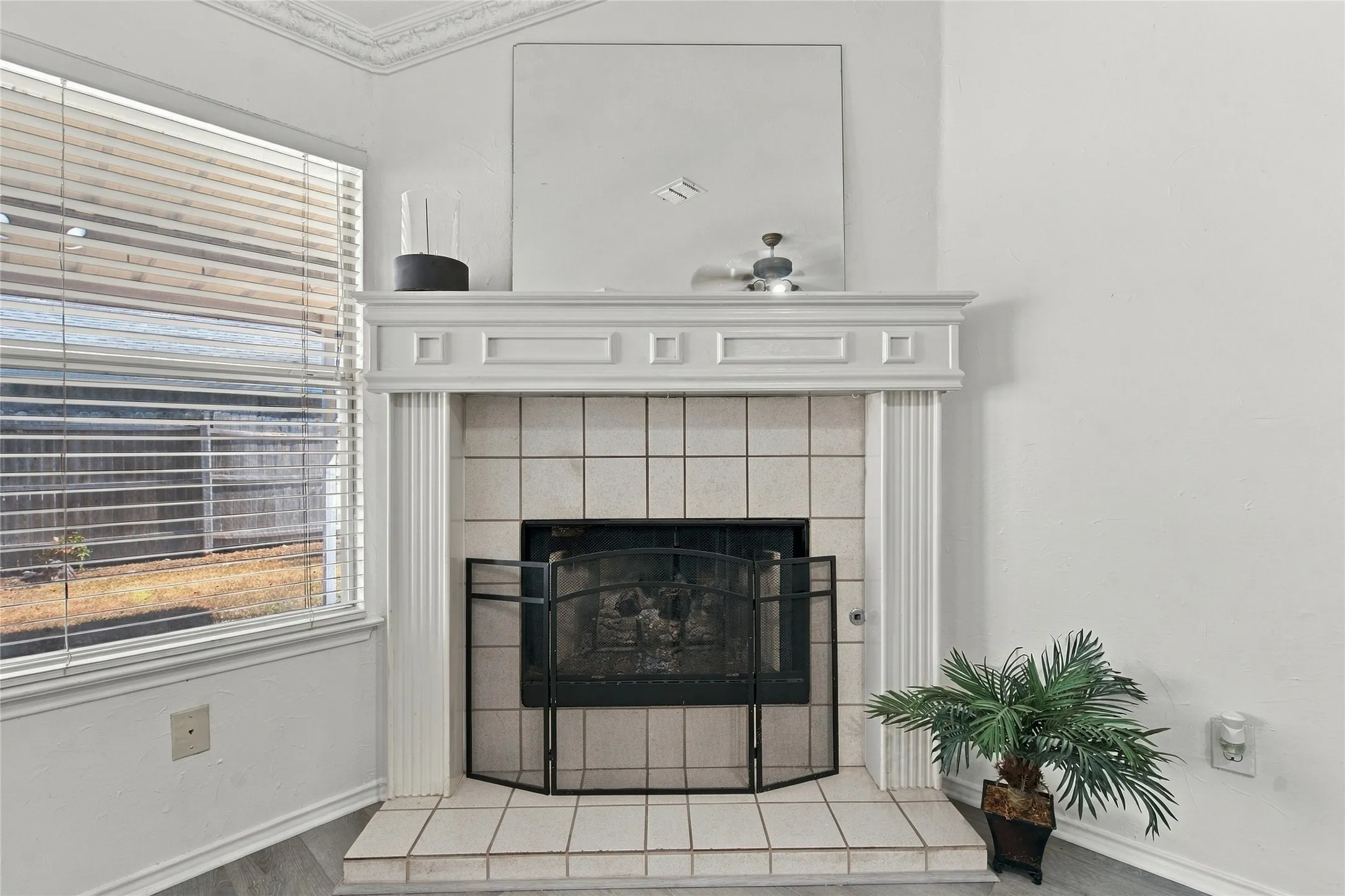 Fireplace with a white mantel, tile surround, and black fire screen